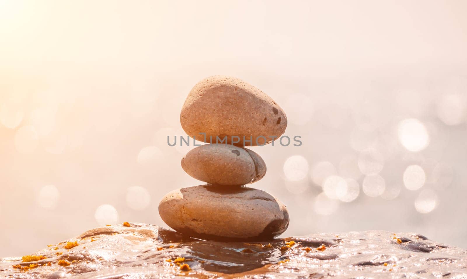 Balanced Pebbles Pyramid on the Beach on Sunny Day and Clear Sky at Sunset. Blue Sea on Background Selective focus, zen stones on sea beach, meditation, spa, harmony, calm, balance concept.