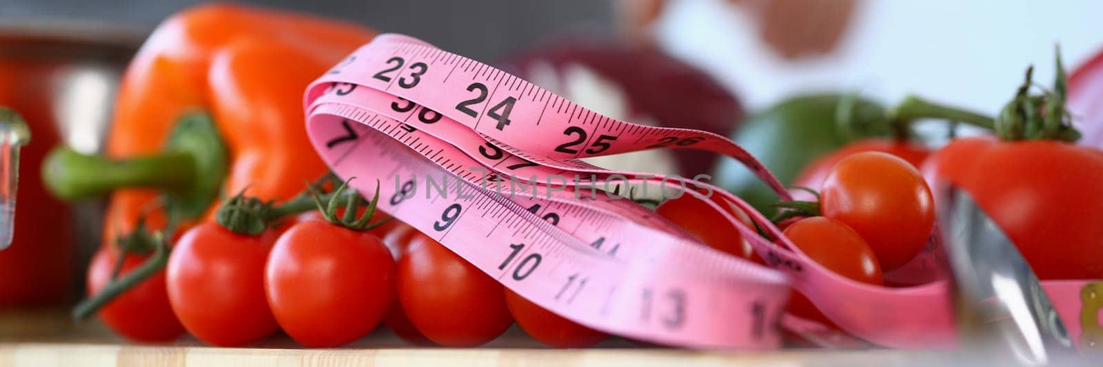 Red tomatoes measuring tape and vegetables in kitchen. Vegetable diet and vitamins concept