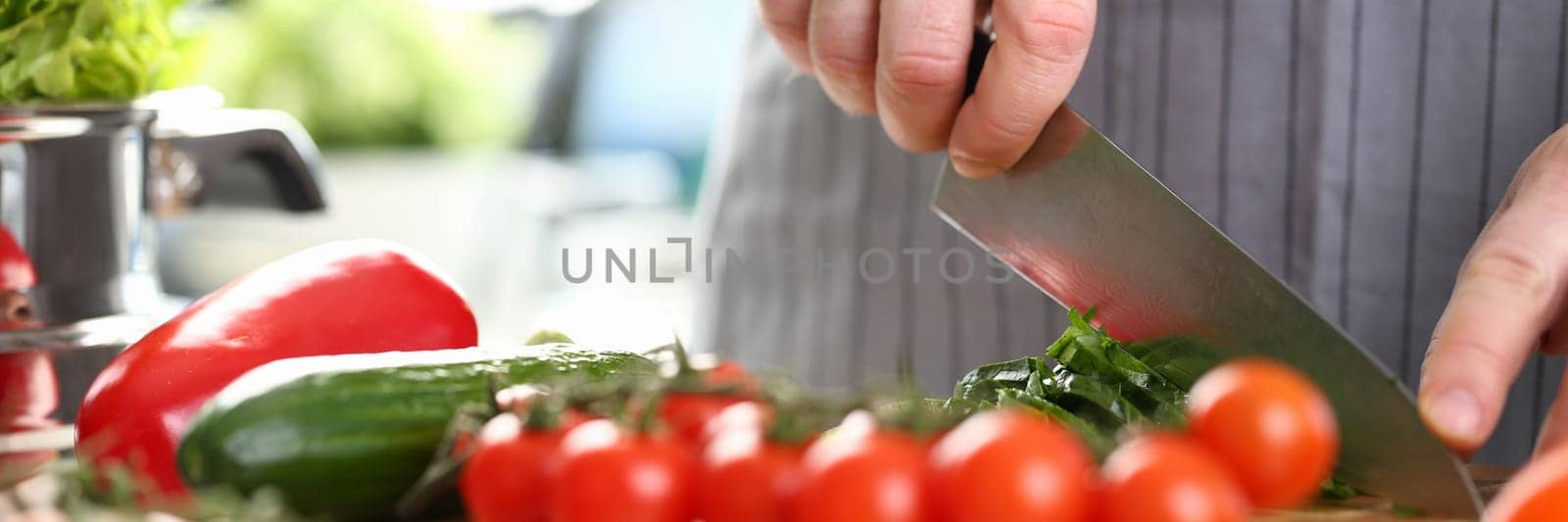 Cook cuts tomatoes and cucumbers on cutting board. Cooking vegetable salad concept