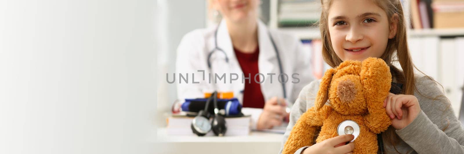 Doctor and child with toy and stethoscope in clinic by kuprevich