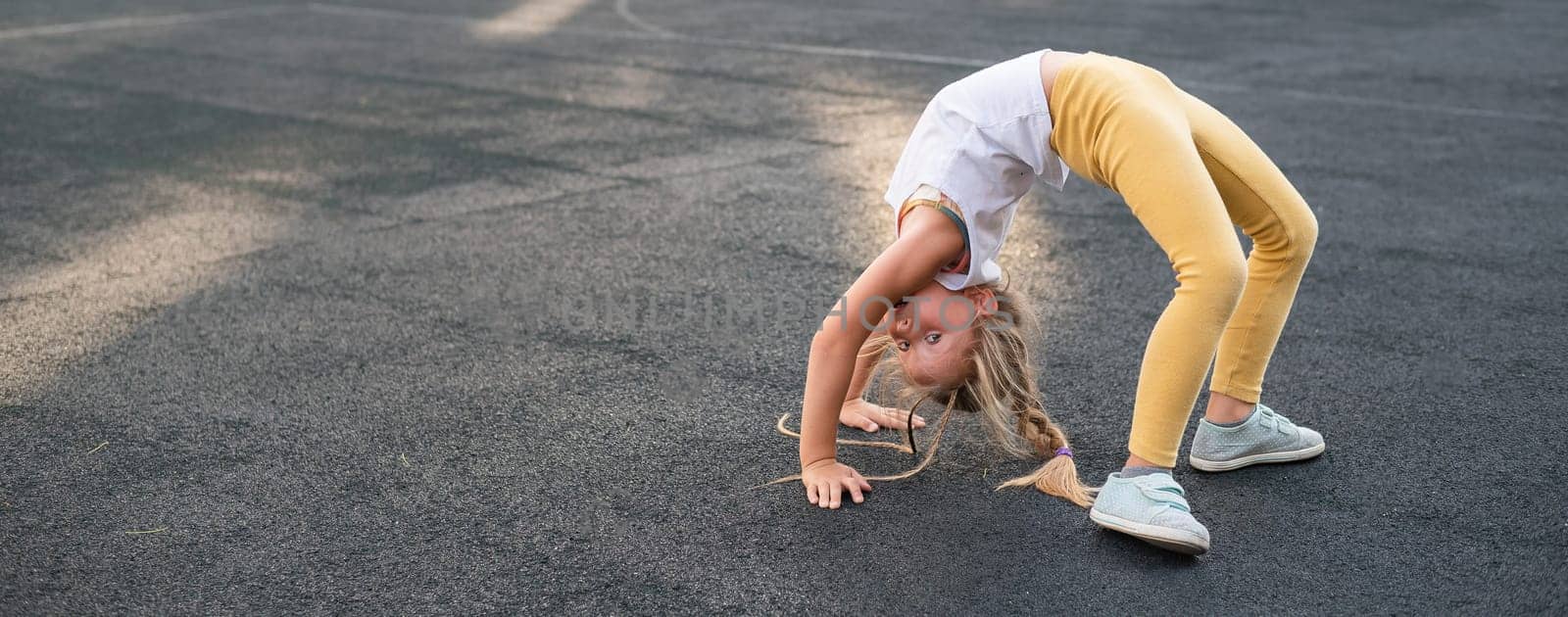 Caucasian girl doing bridge exercise on sports ground outdoors