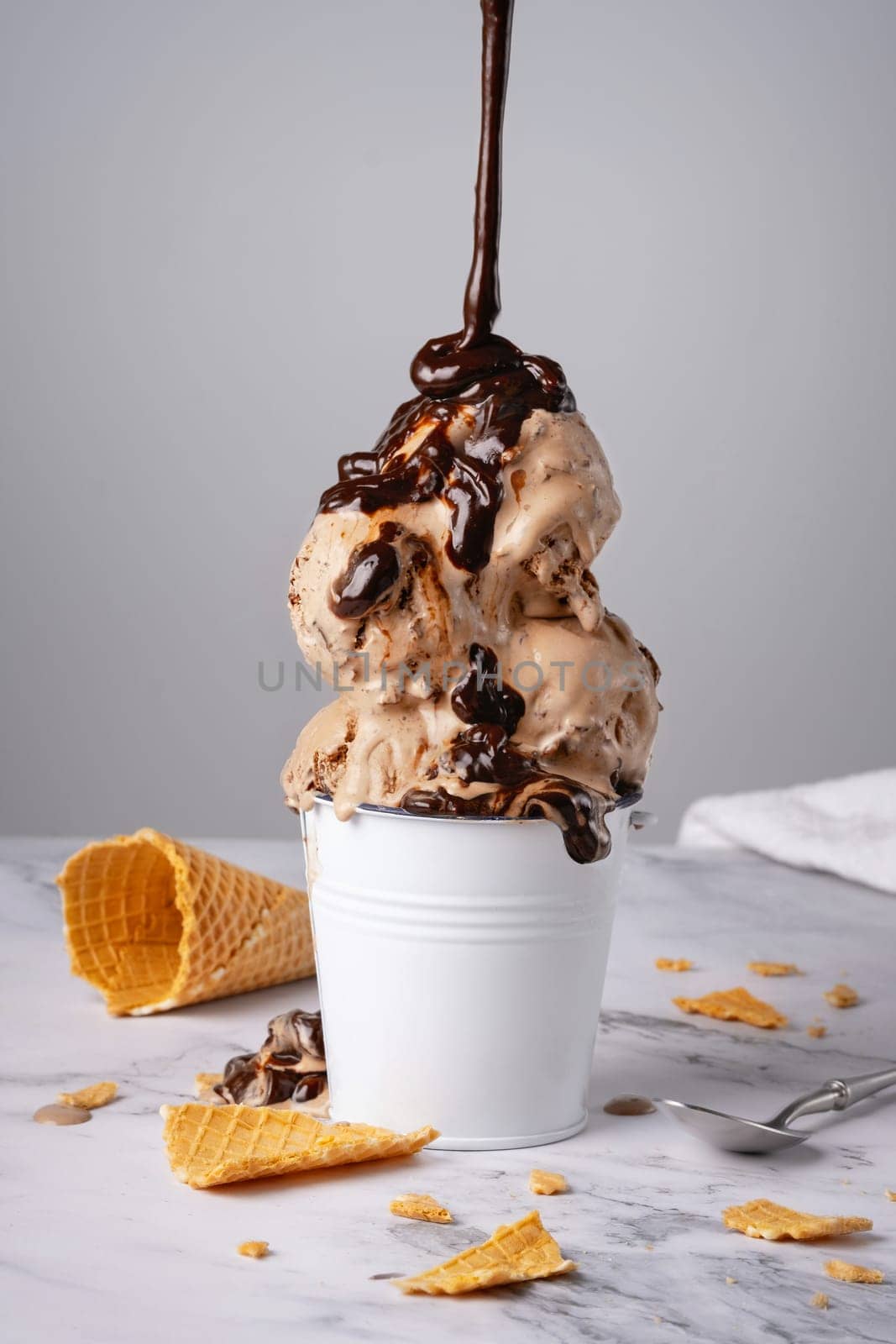 Chocolate ice cream with syrup in a white bucket by NataliPopova