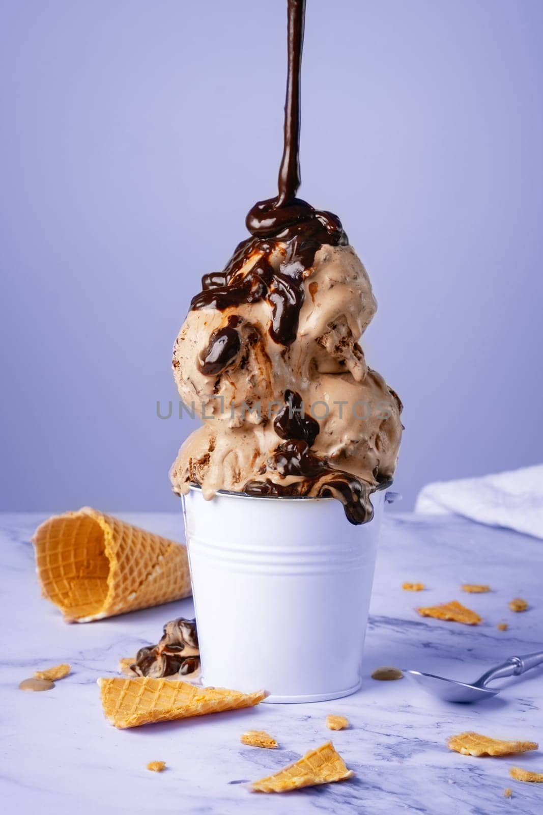 Chocolate ice cream with syrup in a white bucket.