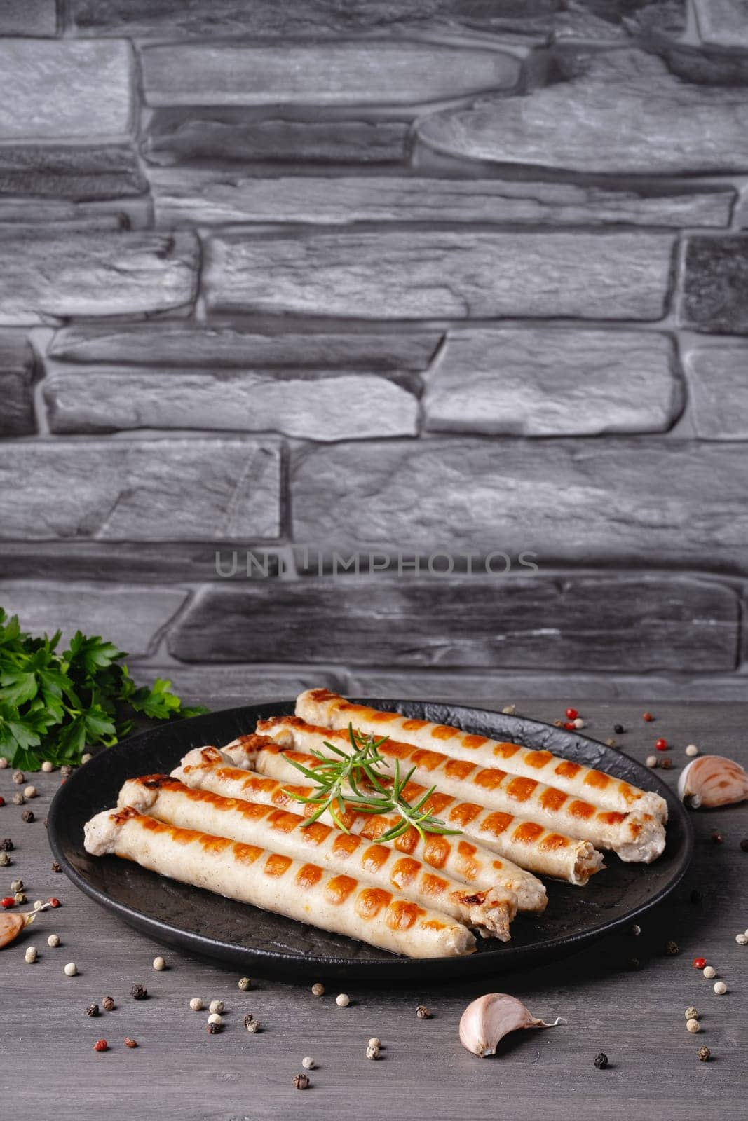 Fresh fried chicken sausages in a plate on a gray table. Empty copy space.