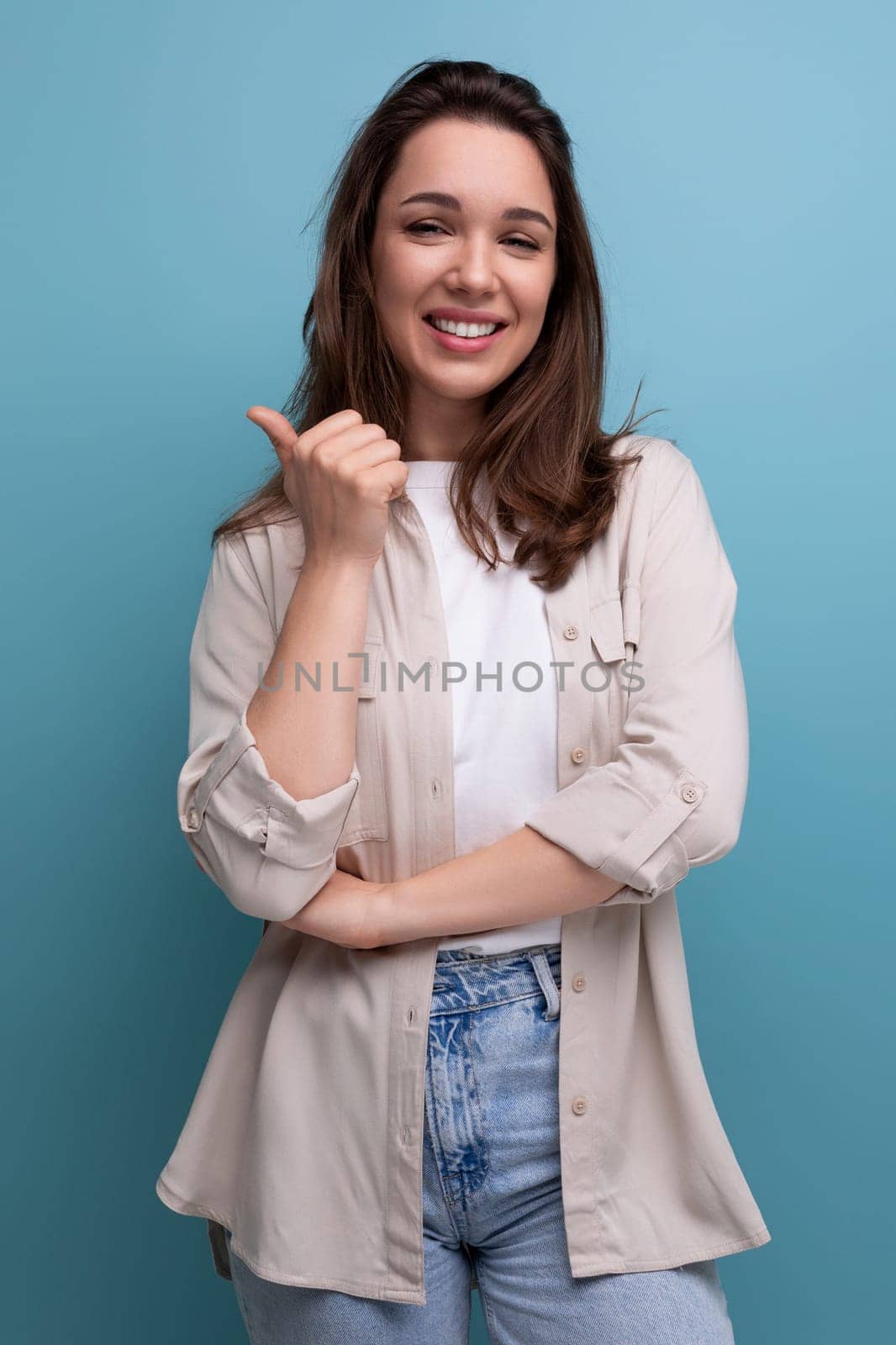 positive brunette young brunette lady dressed in a shirt and jeans shows with her hand that she has an idea.