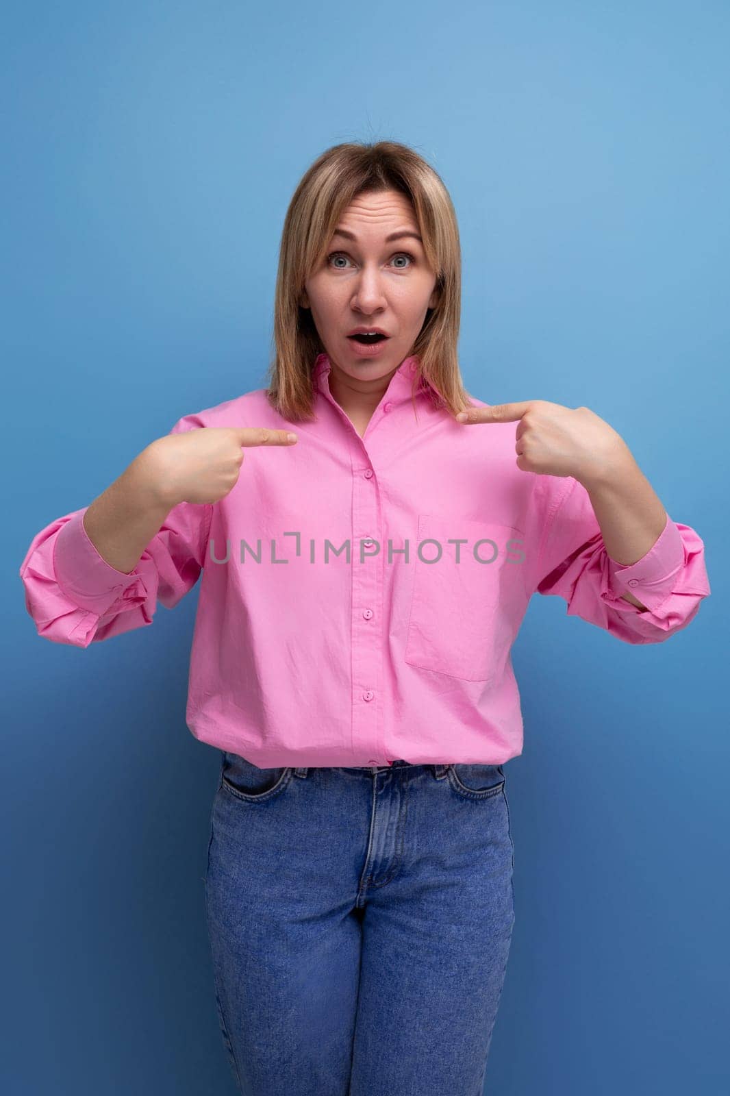 young blond european leader woman with shoulder-length hair in a pink blouse points her finger towards the advertisement by TRMK