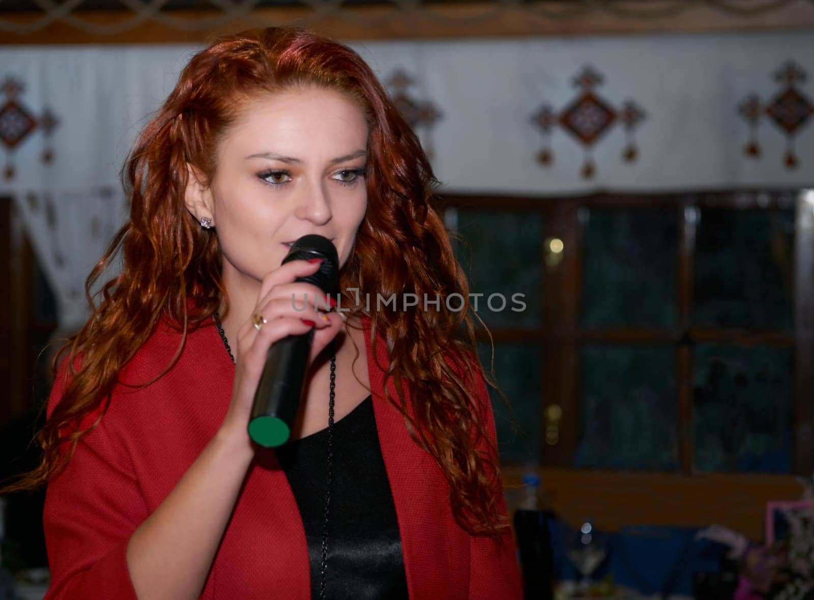 Red haired woman event host speaks with a microphone in a dark room by jovani68