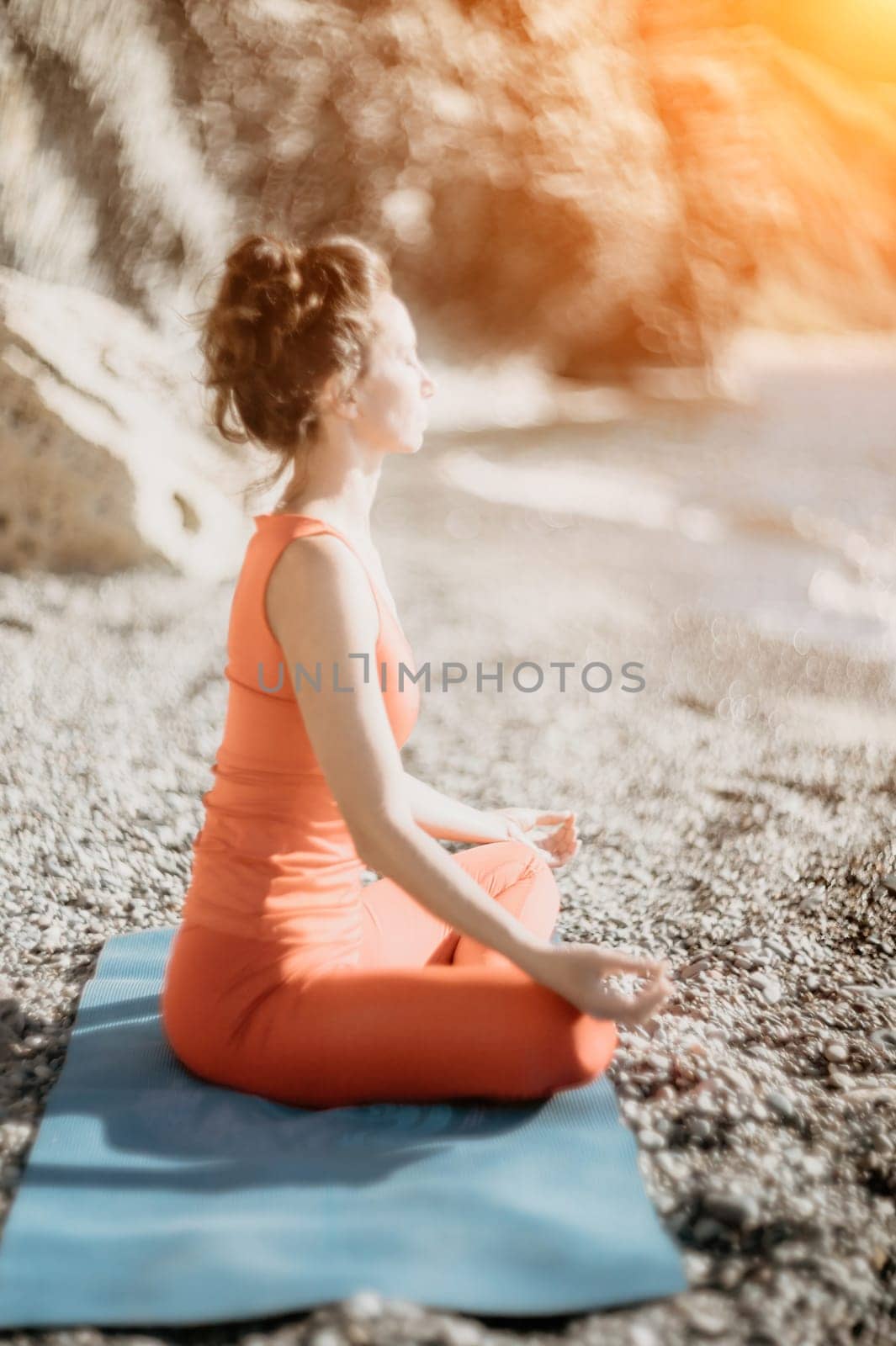 Woman sea yoga. Selective focus. Young beautiful caucasian woman in a red suit practicing yoga on the beach at sunrise near the sea. Yoga. Healthy lifestyle. Meditation concept. by panophotograph
