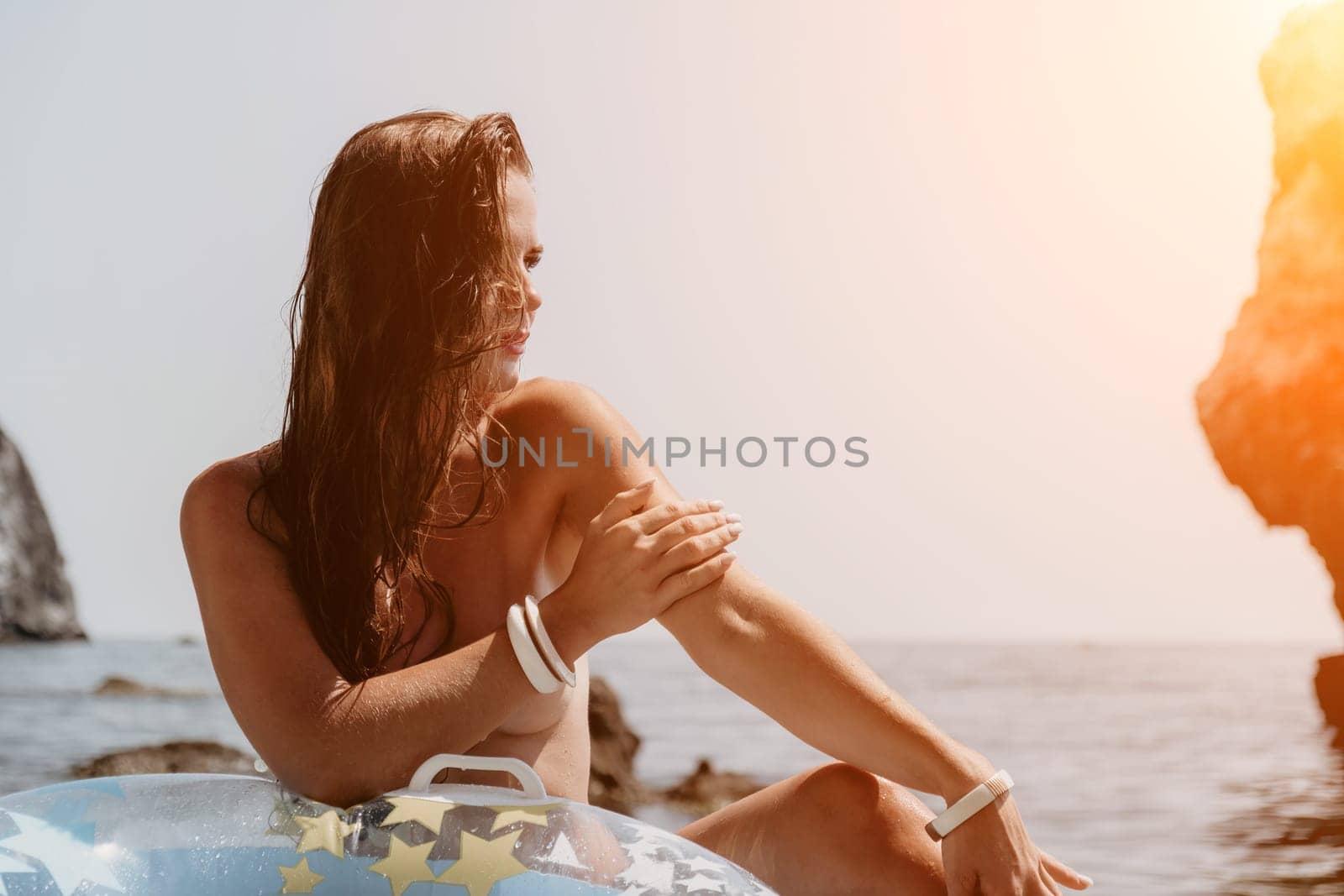 Woman summer sea. Happy woman swimming with inflatable donut on the beach in summer sunny day, surrounded by volcanic mountains. Summer vacation concept