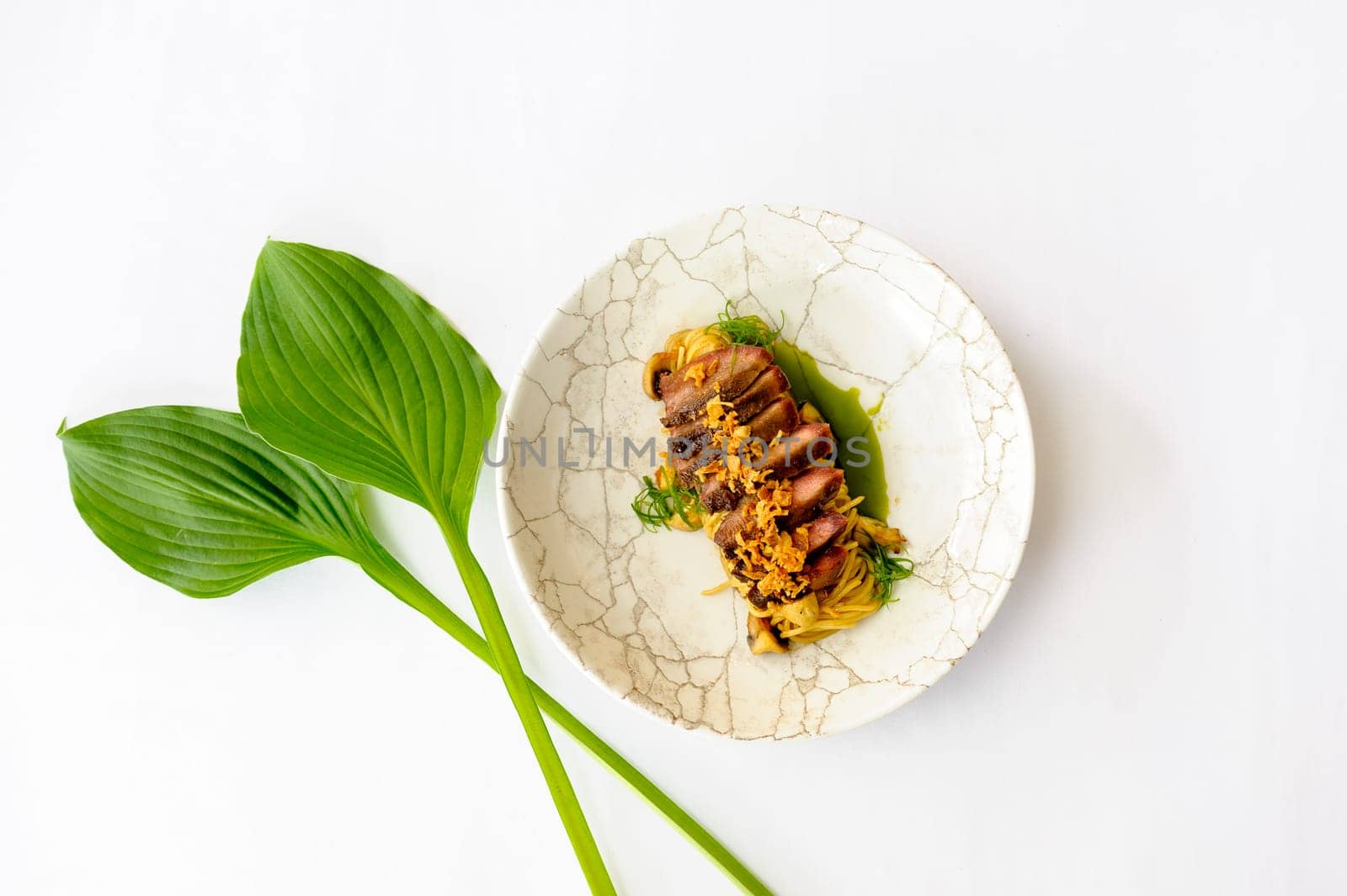 Exquisite serving of beef slices on a white plate on a white background