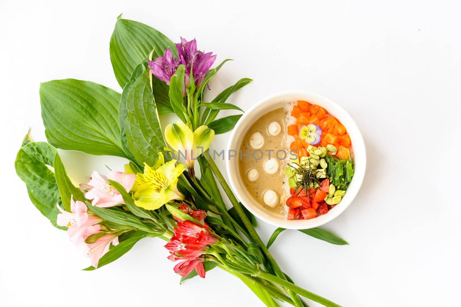 Salmon poke in white dishes decorated with bright flowers on a white background