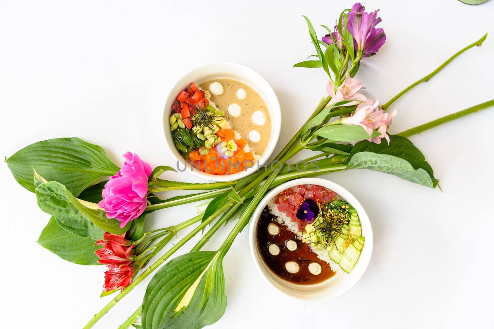 Two poke in white dishes decorated with bright flowers on a white background