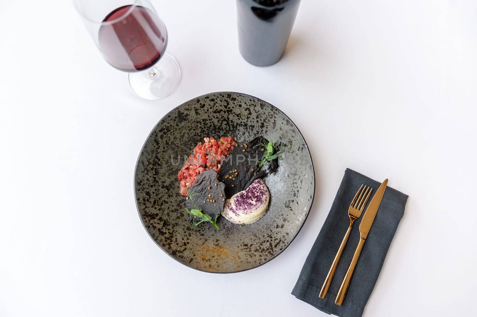 Exquisite serving of beef tartare on a black plate on a white background