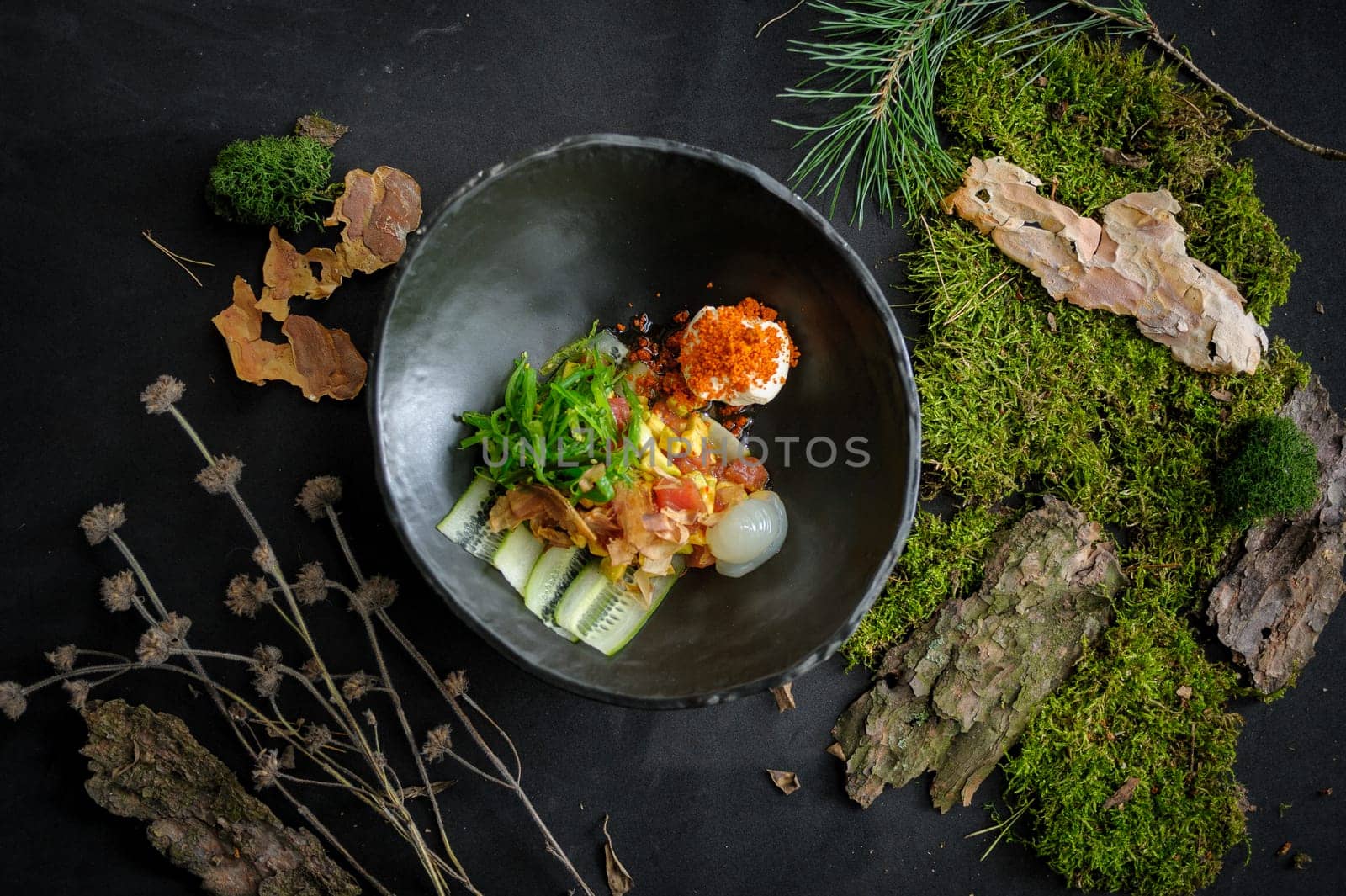 Salad with scallop, wakame, tuna flakes and avocado on a dark background