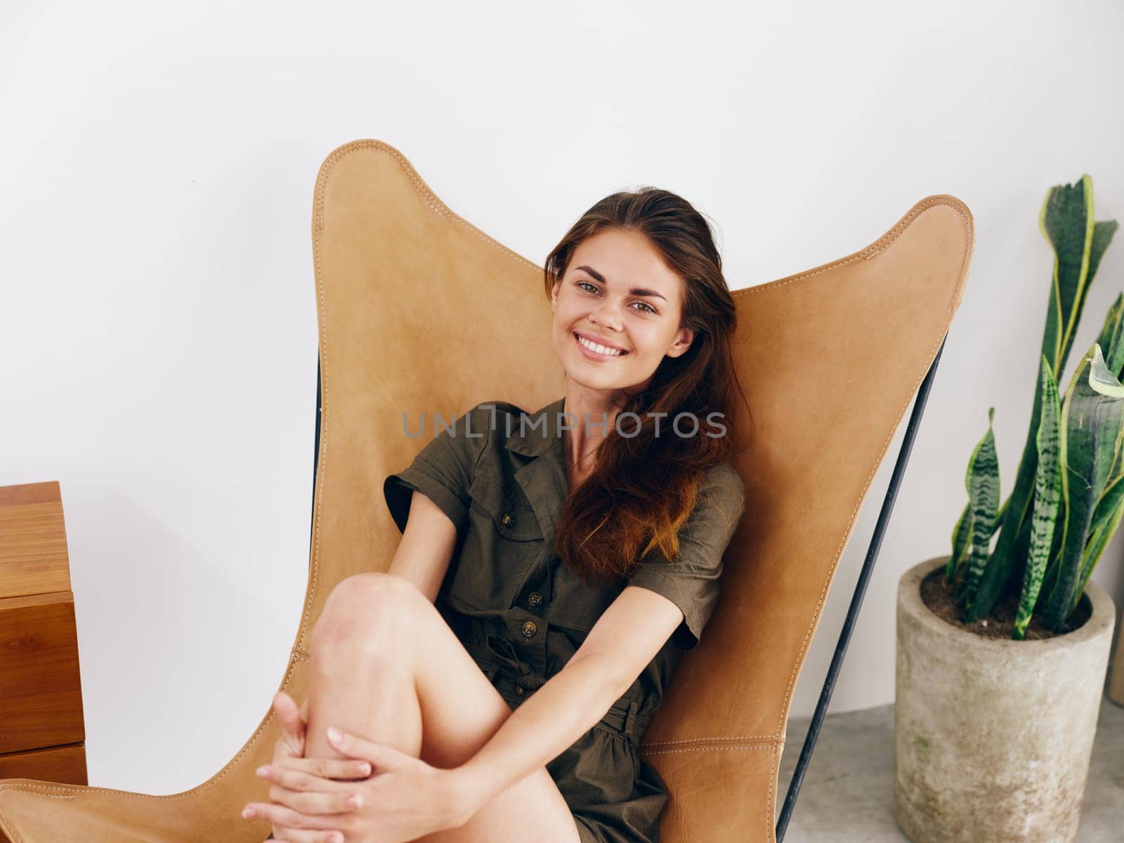 Woman sitting on a chair at home beautiful smile, fun and relaxation, modern stylish interior scandia lifestyle, copy space. by SHOTPRIME