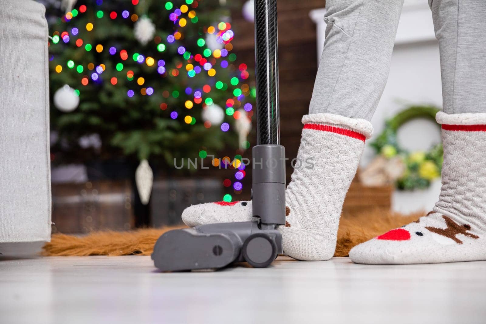 Suction tip from a vacuum cleaner pressed with a foot. Christmas cleaning in the living room. Second plan in blur e bokeh effect.