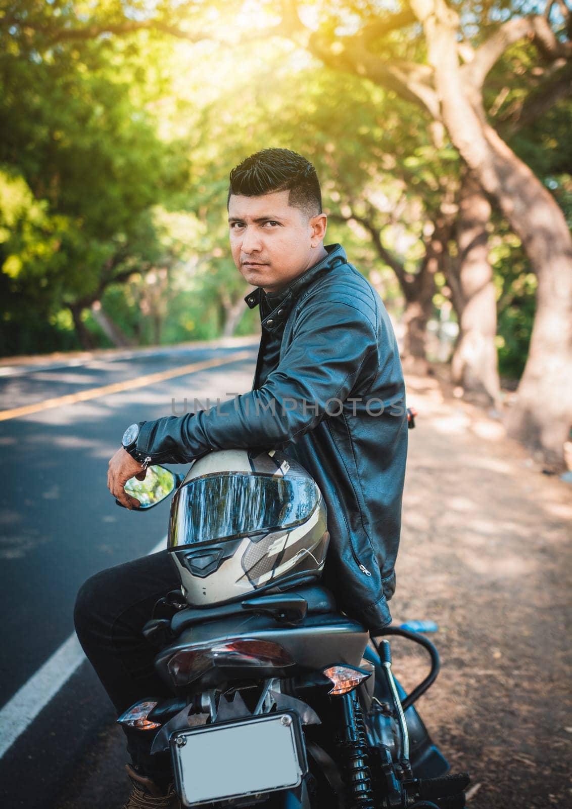 Portrait of handsome man sitting on his motorbike at the roadside. Portrait of biker sitting on his motorcycle at the side of the road by isaiphoto