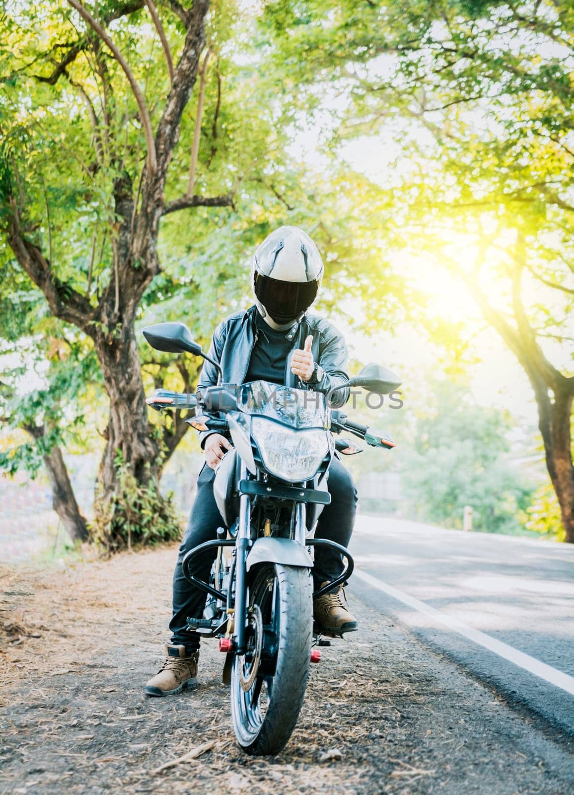 Motorcyclist in safety helmet with thumb up on the road. Biker wearing safety helmet with thumb up on the road by isaiphoto