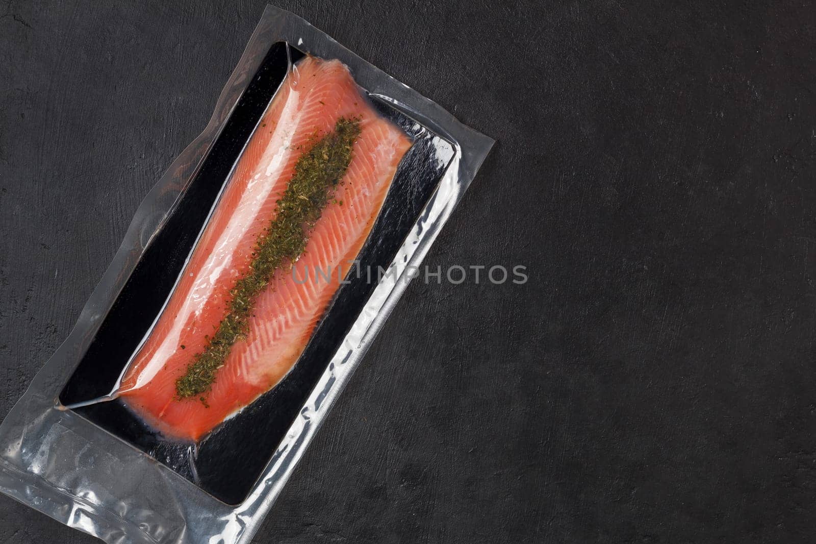 Fish fillet in vacuum packaging, on a black background. Red fish, trout.Copy space by lara29