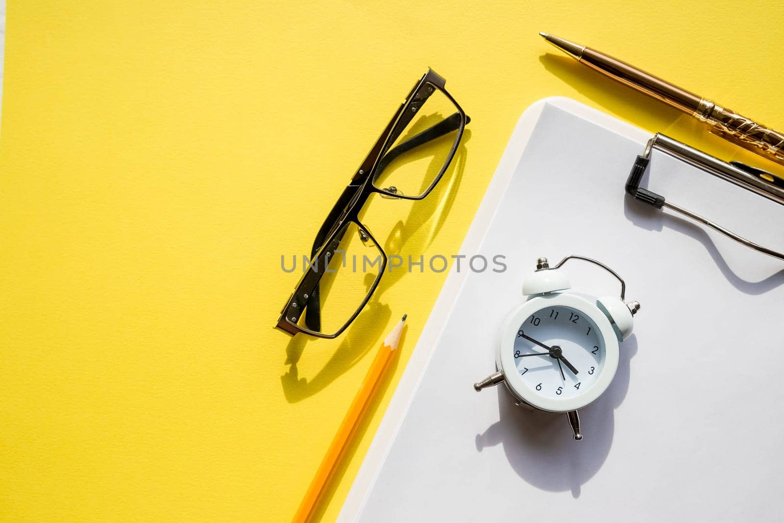 Clear notebook, cup of coffee, glasses, pen and books on yellow table,