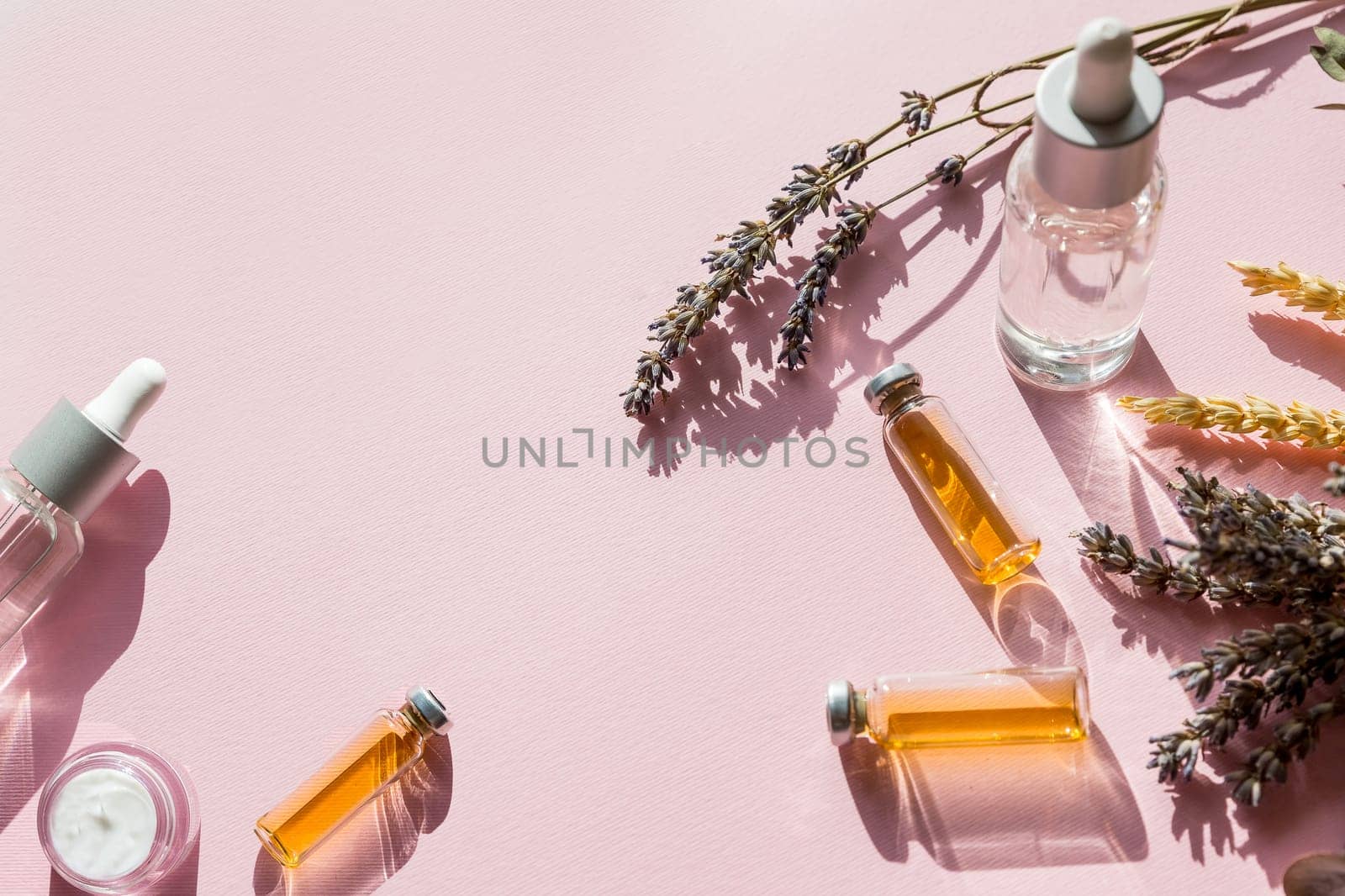 Bottle of essential oil with fresh herbal sage, rosemary, thyme and peppermint setup with flat lay on white wooden table.