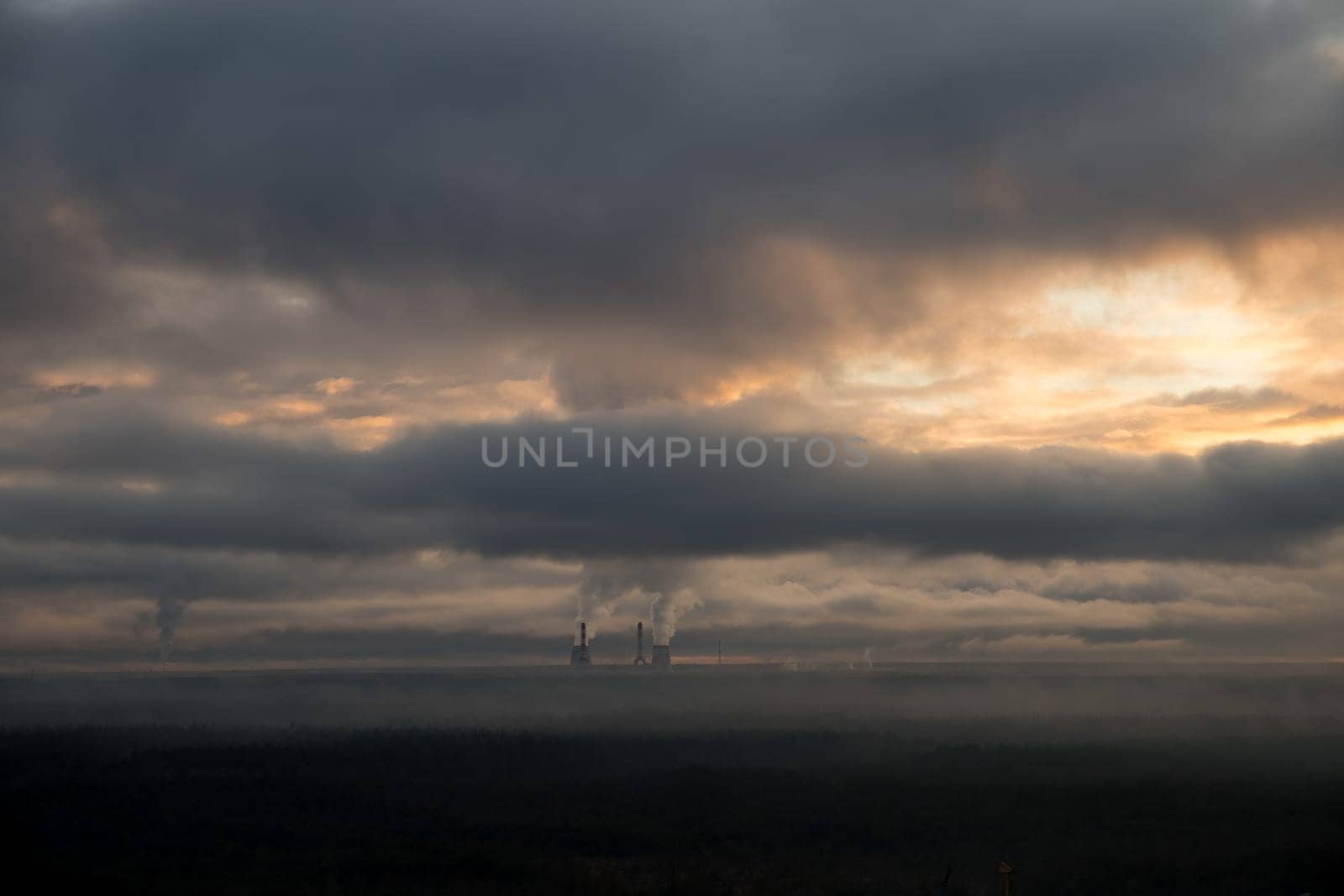 Red brick industrial building with large pipe. Dramatic sunset sky. Environment, ecology, pollution, alternative energy and natural gas production concepts