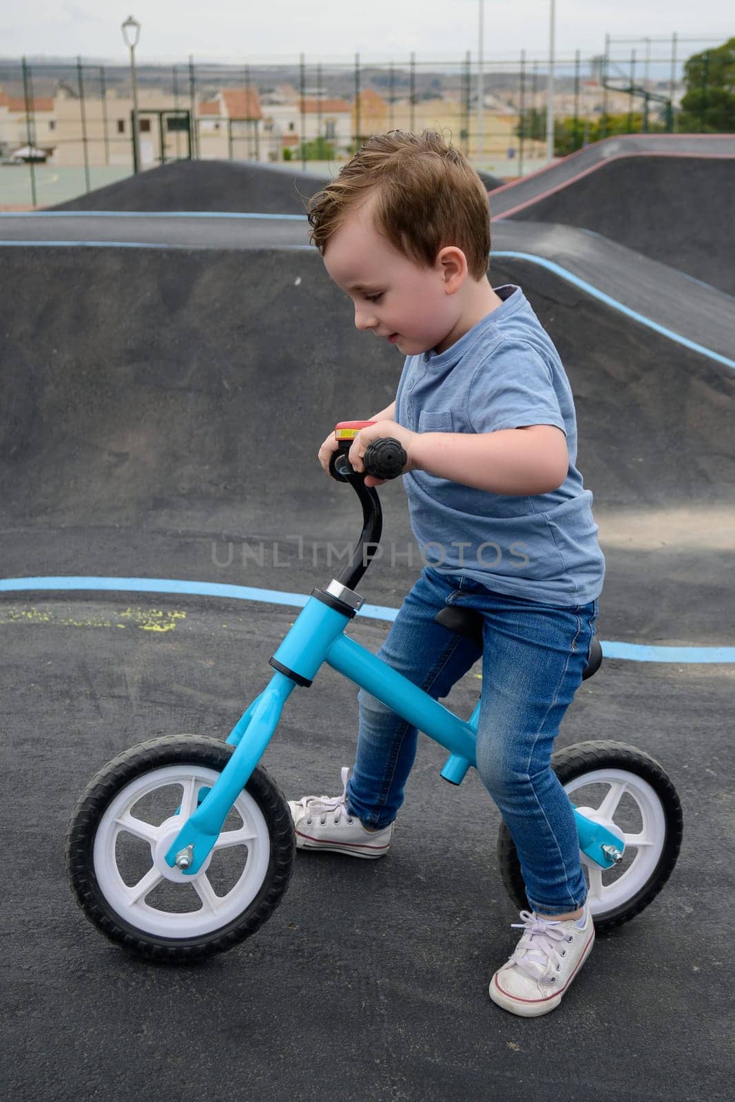 A young child rides the new South Glenmore Park BMX pump track on his bike on a summer evening in Calgary Alberta Canada. by jcdiazhidalgo