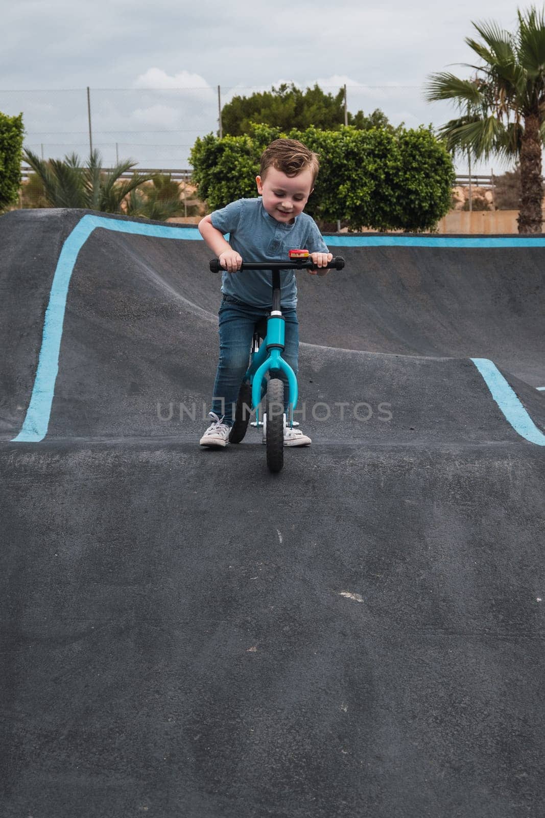 A young child rides the new South Glenmore Park BMX pump track on his bike on a summer evening in Calgary Alberta Canada. by jcdiazhidalgo