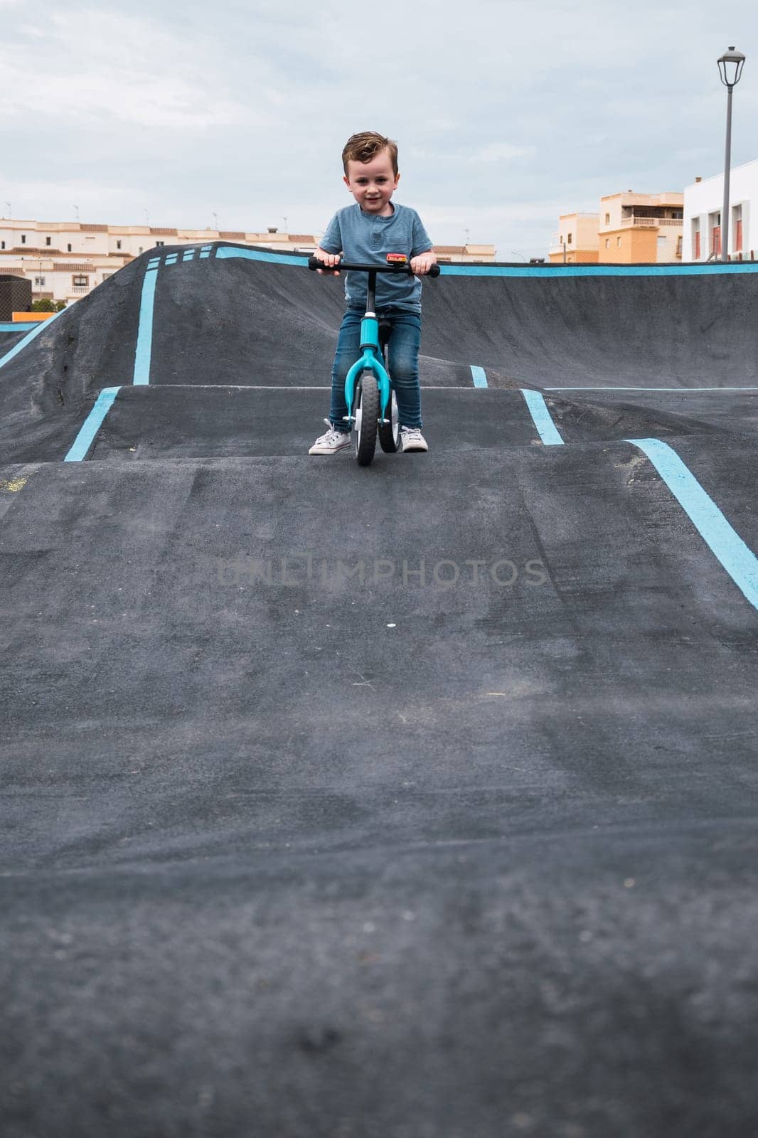A young child rides the new South Glenmore Park BMX pump track on his bike on a summer evening in Calgary Alberta Canada.