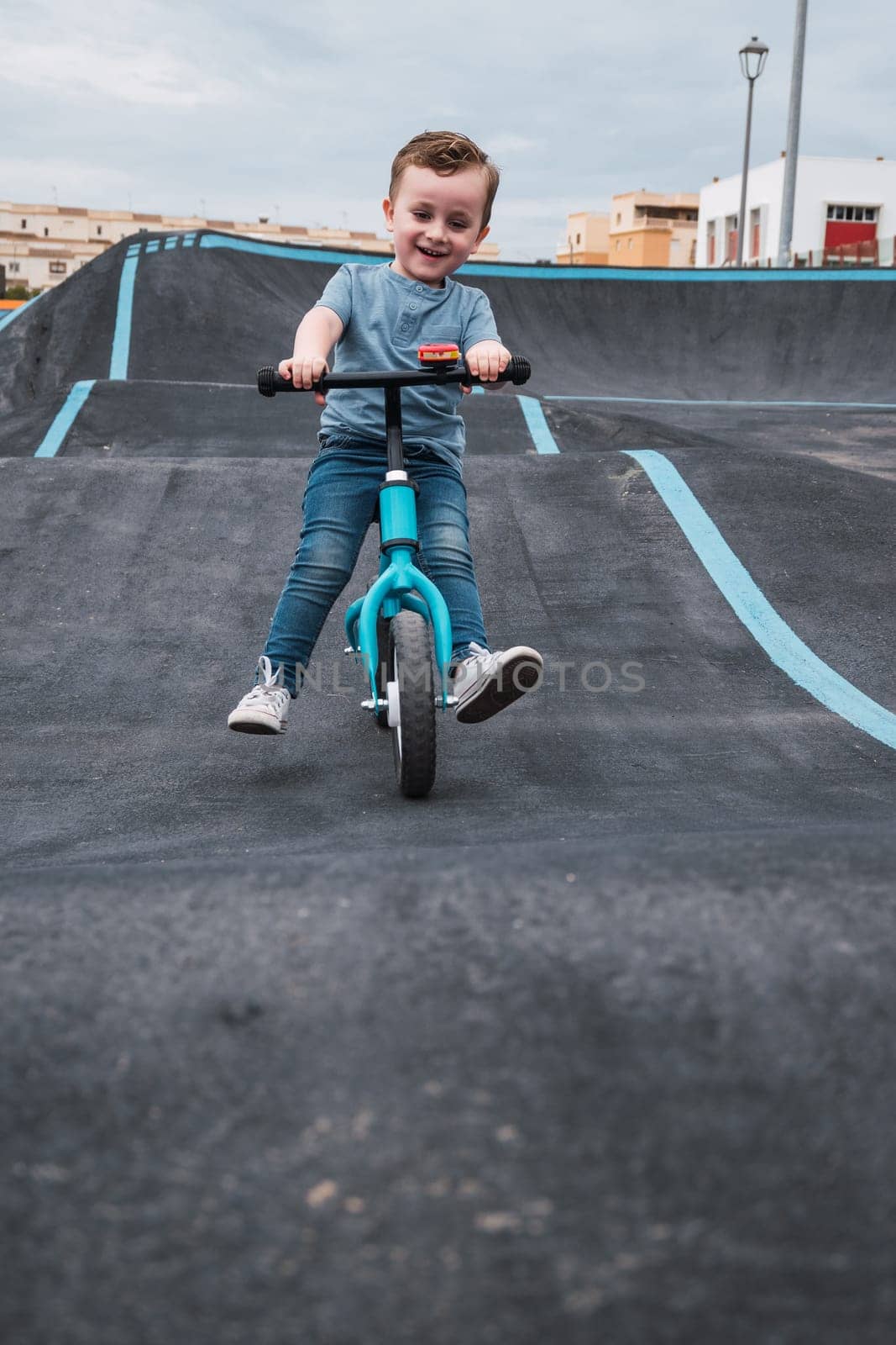 A young child rides the new South Glenmore Park BMX pump track on his bike on a summer evening in Calgary Alberta Canada.