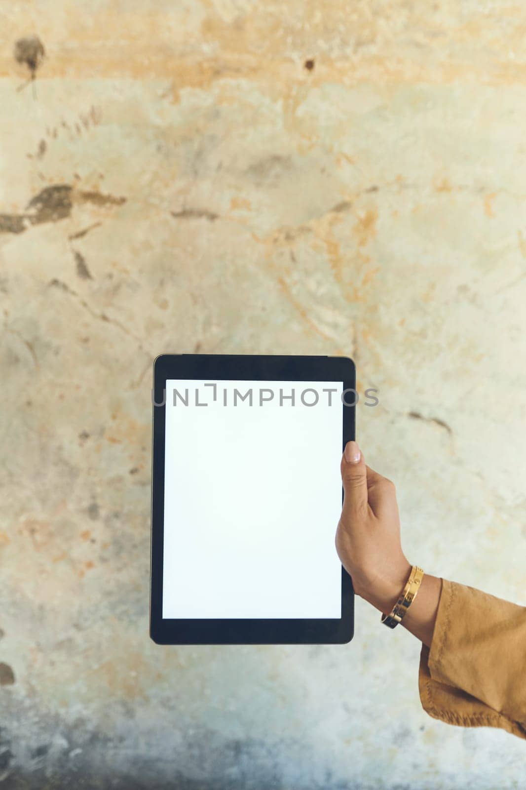 Selling something Do it online. Closeup shot of an unrecognisable woman holding a digital tablet with a blank screen against a wall. by YuriArcurs