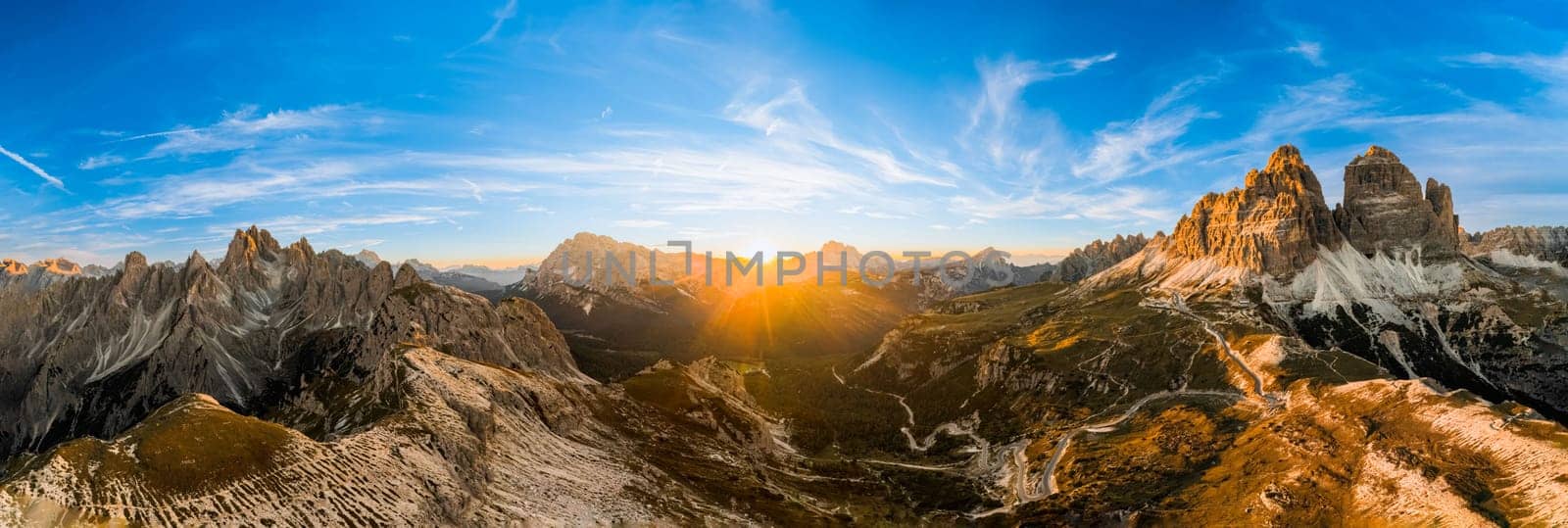 Rocky mountains rise above deep canyons. Mountain landscapes of primeval nature under blue sky. Tre Cime di Lavaredo at sunset aerial view