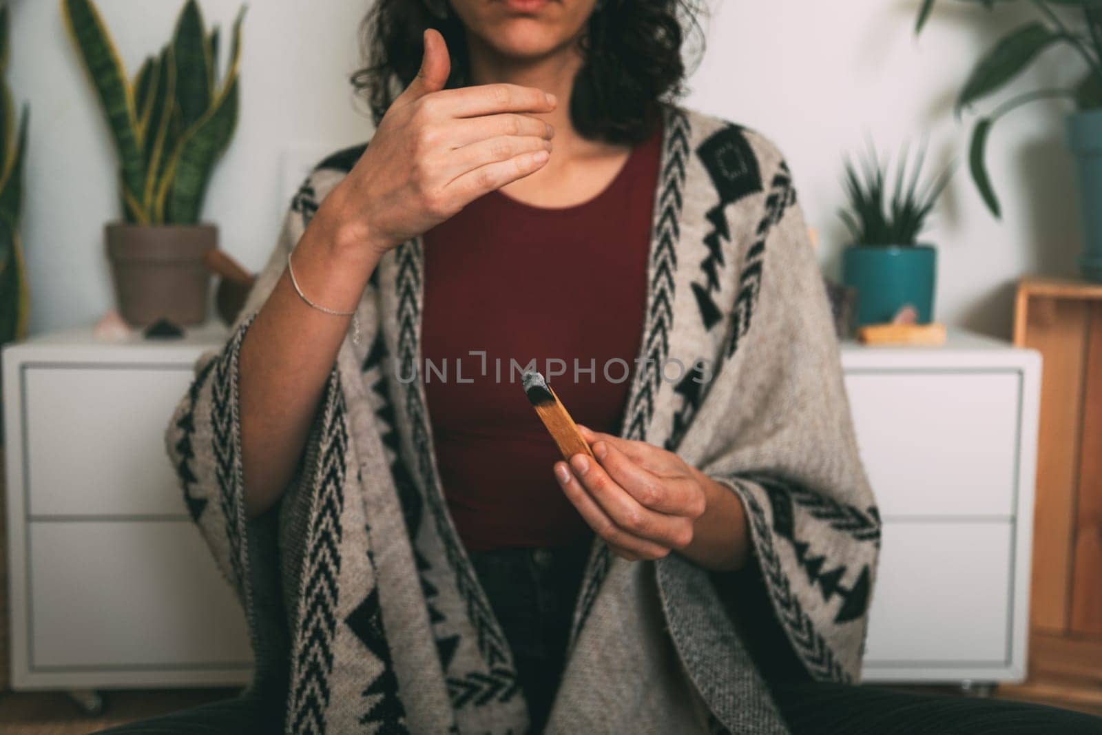 woman meditating with a palo santo dressed with a handmade poncho.background with copy space. concept meditation. horizontal image