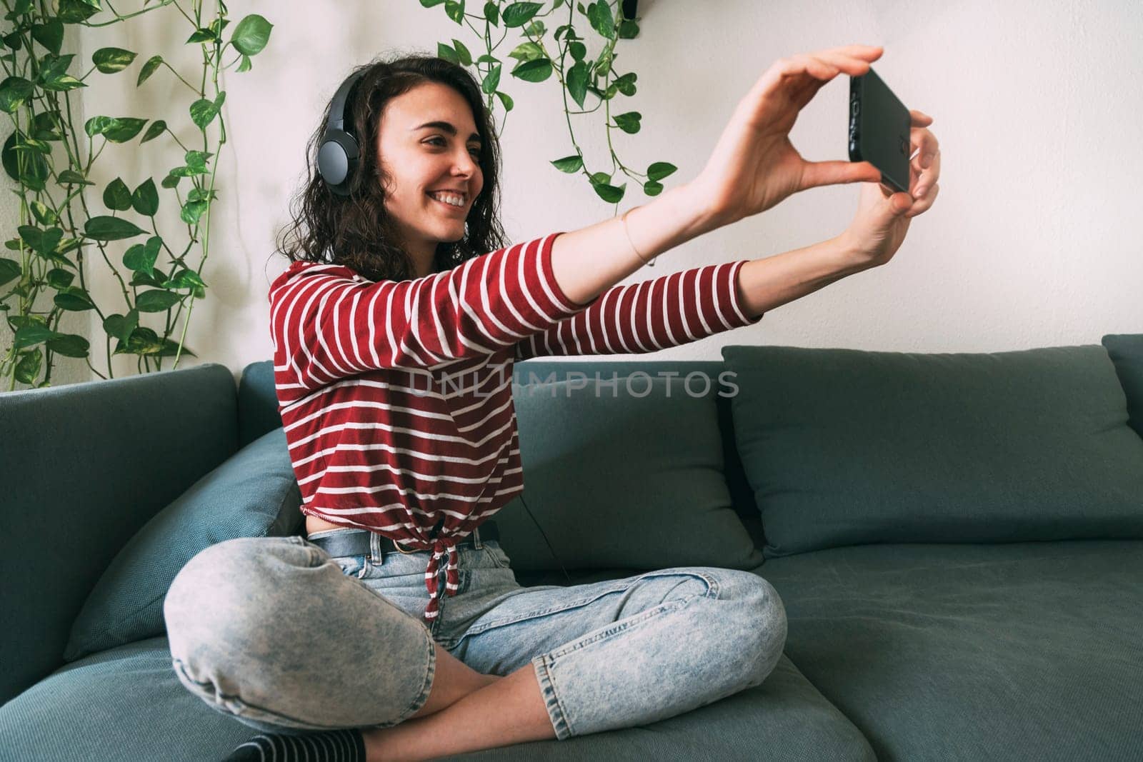 Girl with headphones taking a picture with her phone at home. Technology concept
