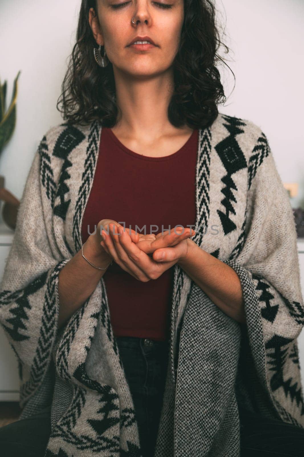 woman meditating with her hands in the form of an offering dressed in a handmade poncho