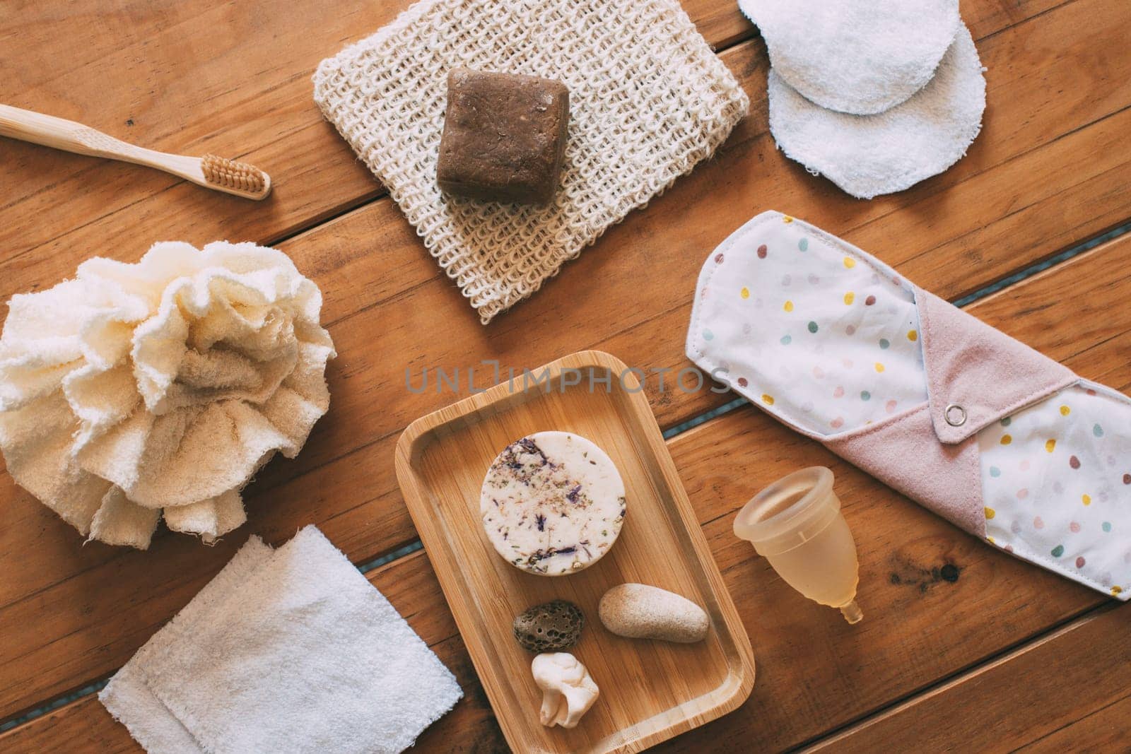 Natural and ecological women's personal hygiene products in natural wood base. solid natural handmade shampoo. Bamboo toothbrush. Reusable cotton make-up removal wipes. Reusable cloth pad. Reusable cloth sponge. Menstrual cup. Zero waste concept. Ecological concept. Environmental sustainability concept