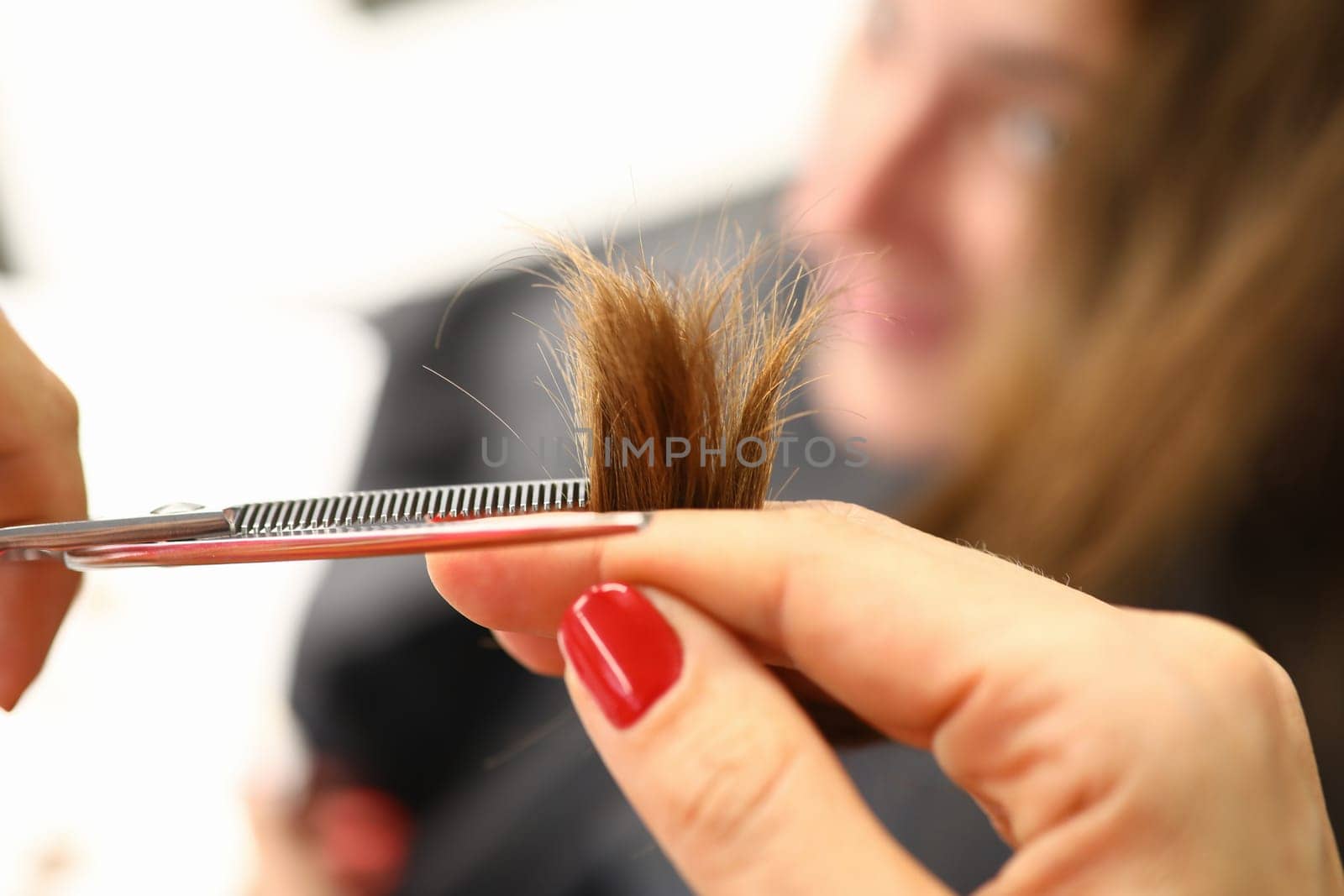 Cutting split ends with scissors closeup, hairdresser cuts brown hair with scissors. haircut closeup. Get rid of those split ends