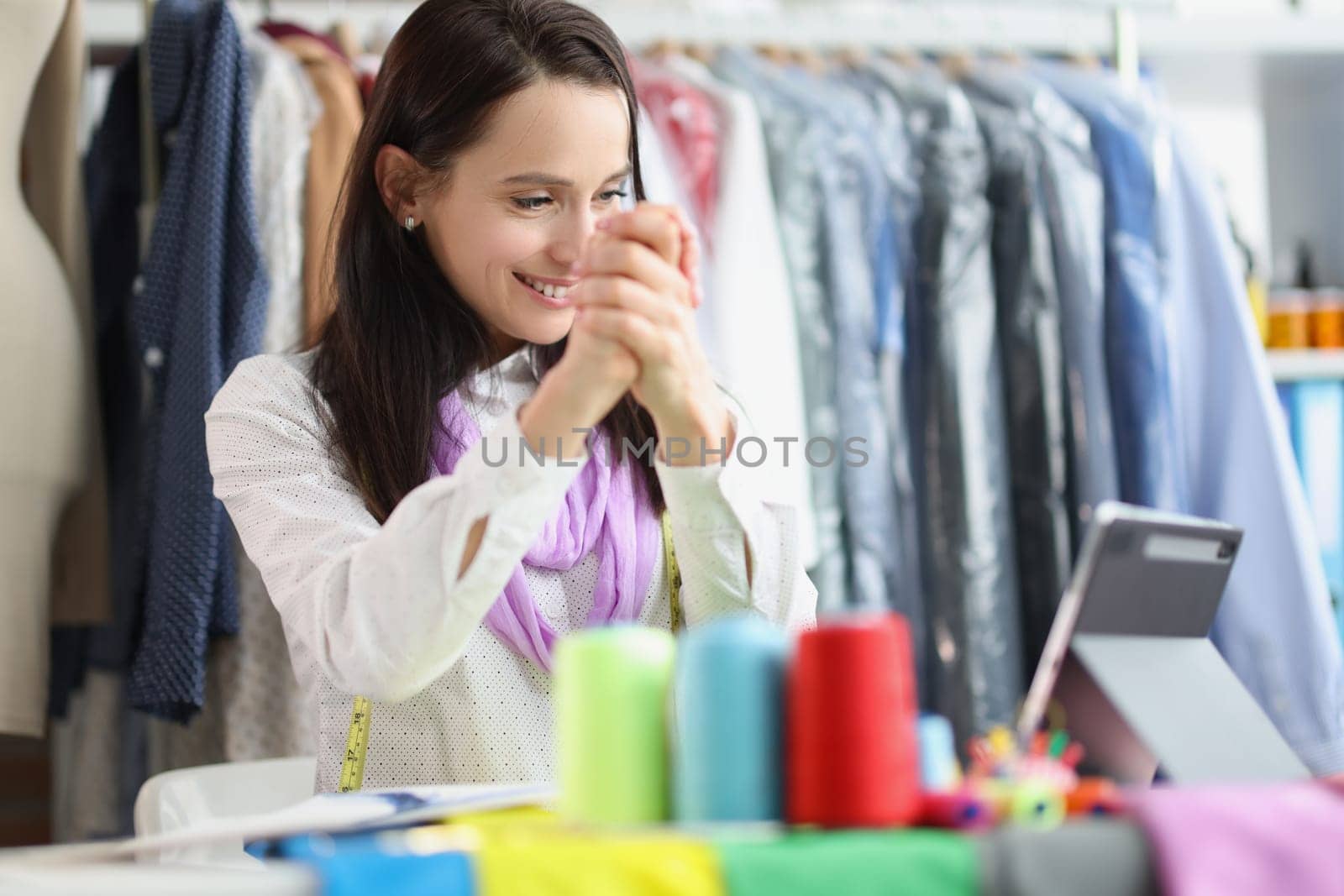 Smiling female seamstress stylist talking on video call on tablet by kuprevich