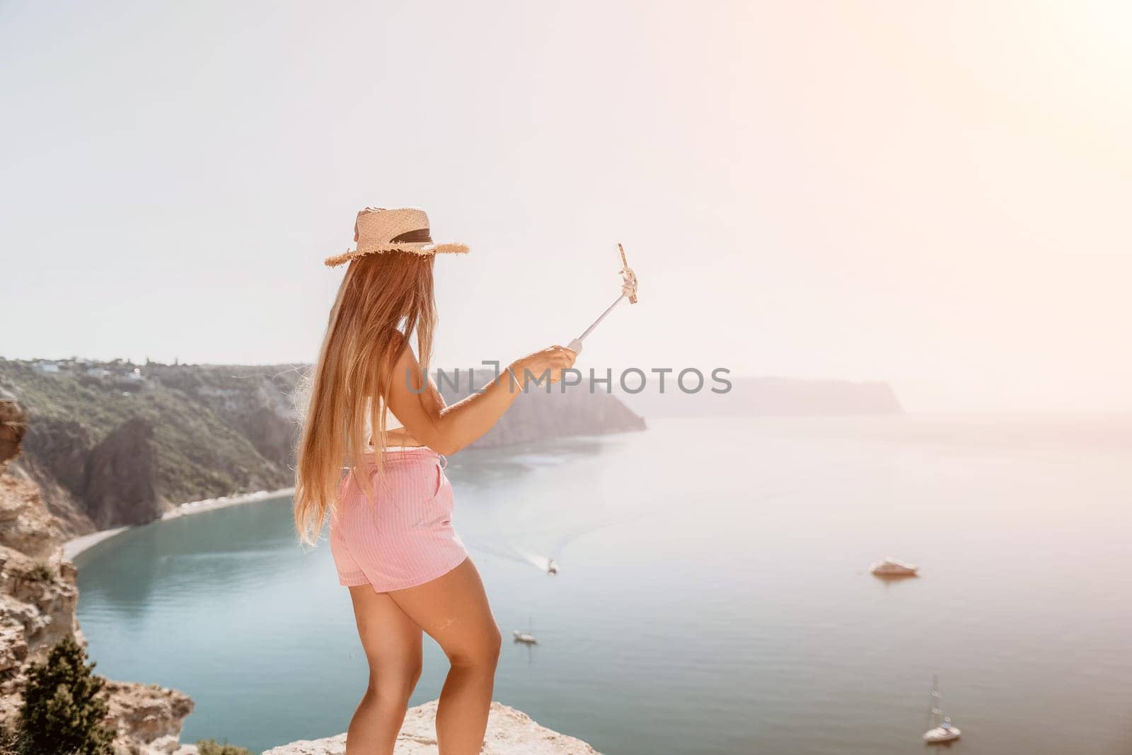 Digital nomad, Business woman working on laptop by the sea. Pretty lady typing on computer by the sea at sunset, makes a business transaction online from a distance. Freelance remote work on vacation