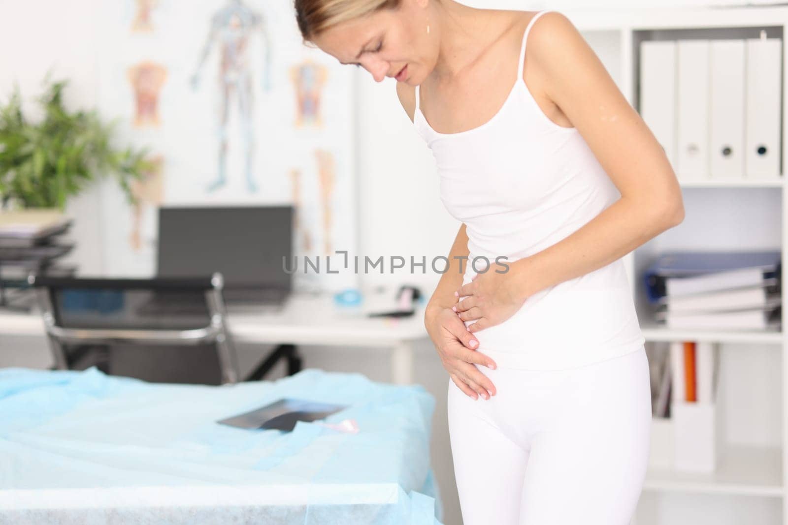 Woman with severe abdominal pain in clinic. Menstruation, gastritis abortion concept