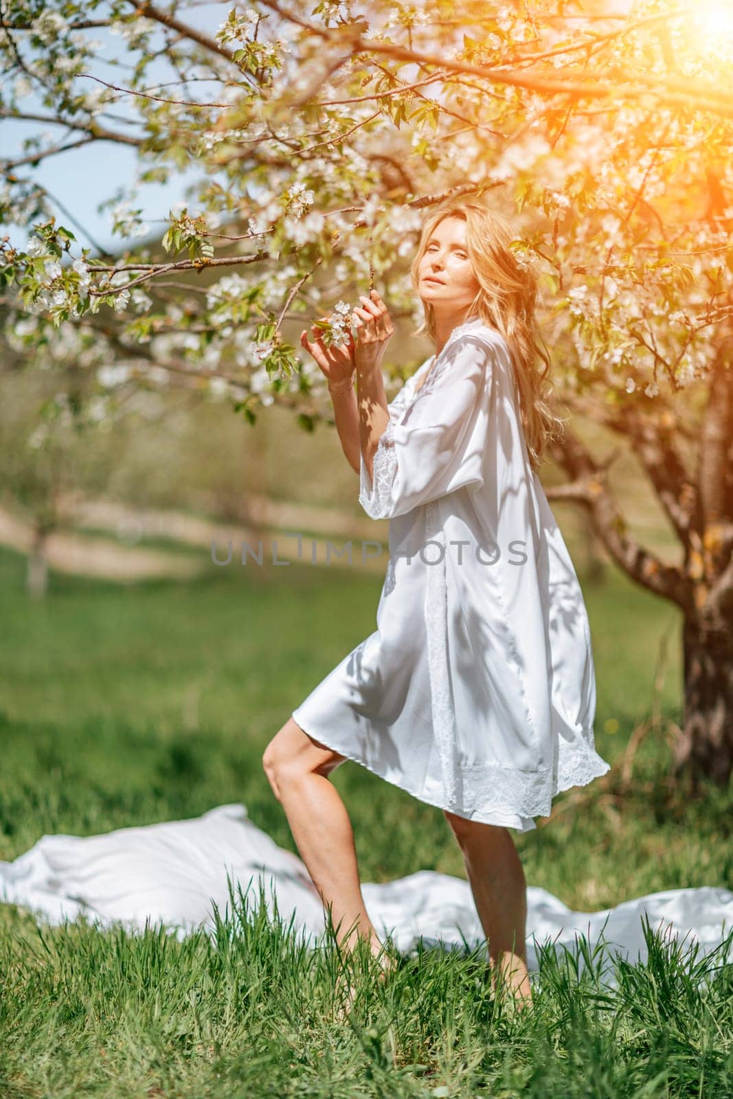 Blond garden. Portrait of a blonde in the park. Happy woman with long blond hair in a blue dress. by Matiunina