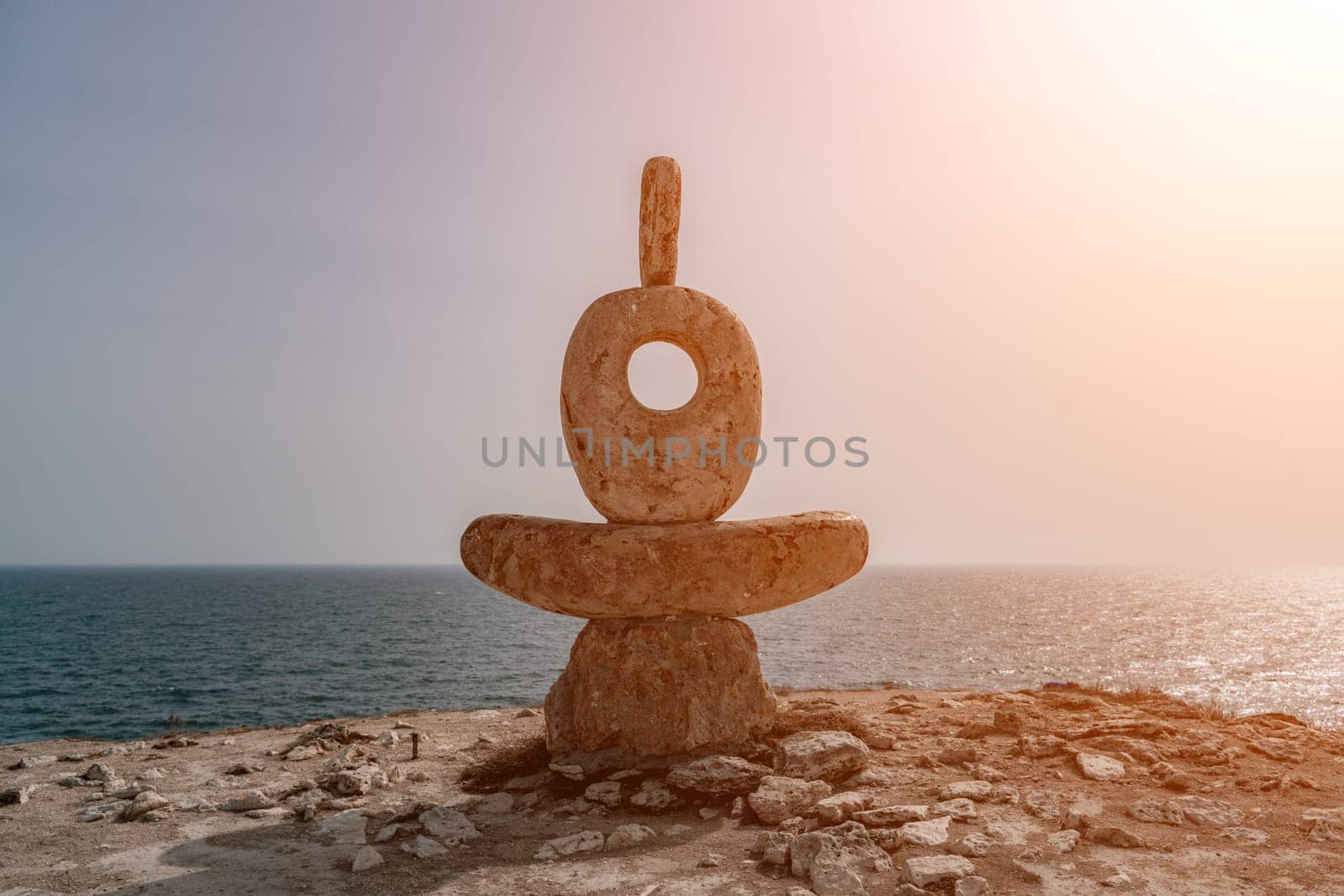 Sculpture symbol made of large pebbles against the blue sky by Matiunina