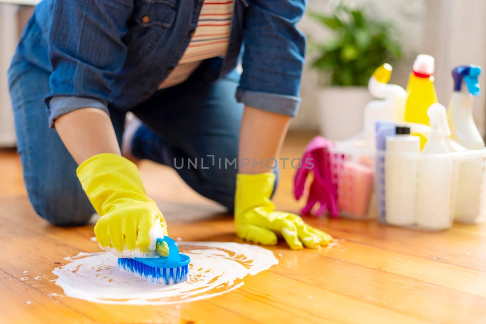 Woman in rubber gloves is using floor brush to cleaning floor. Housekeeping and cleaning concept.