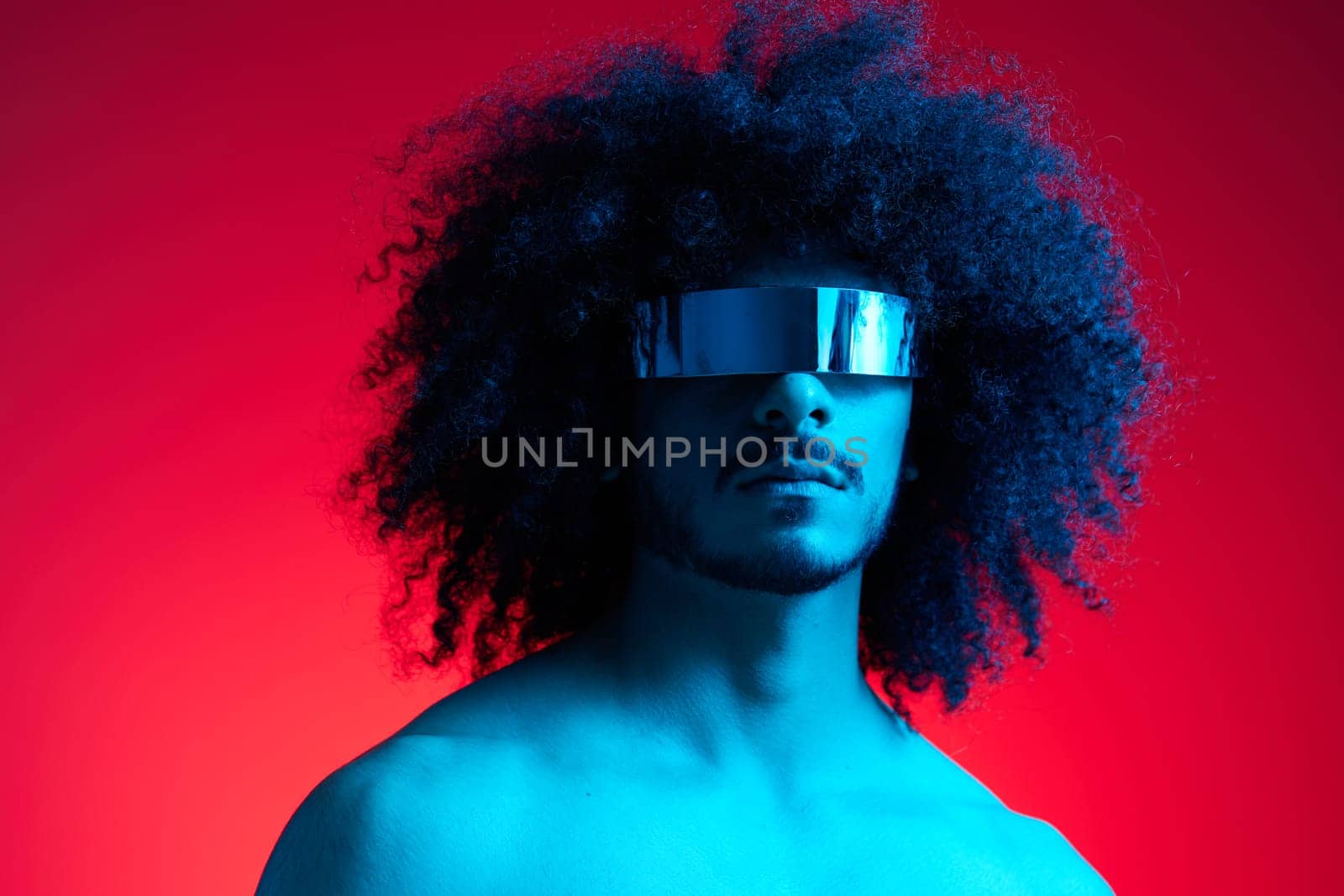 Portrait of fashion man with curly hair on red background with stylish glasses, multinational, colored light, black leather jacket trend, modern concept, sexy body. High quality photo