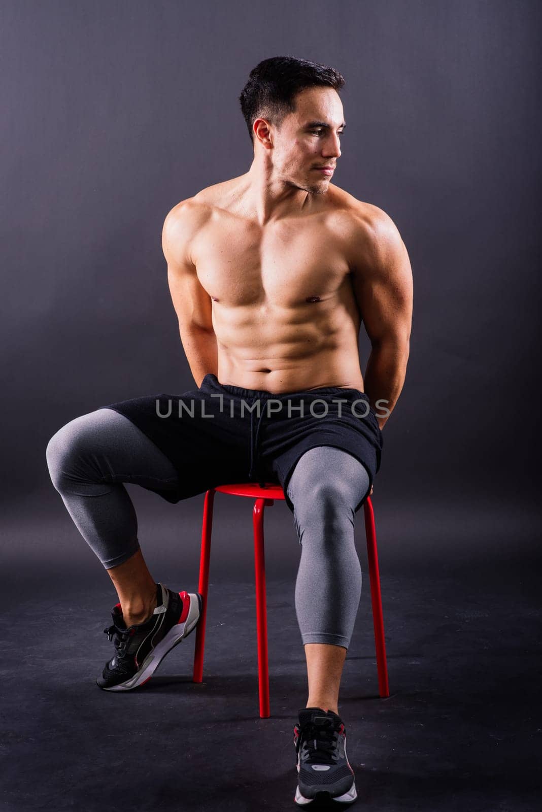 Muscular shirtless young man standing confident, front view, looking at camera by Zelenin