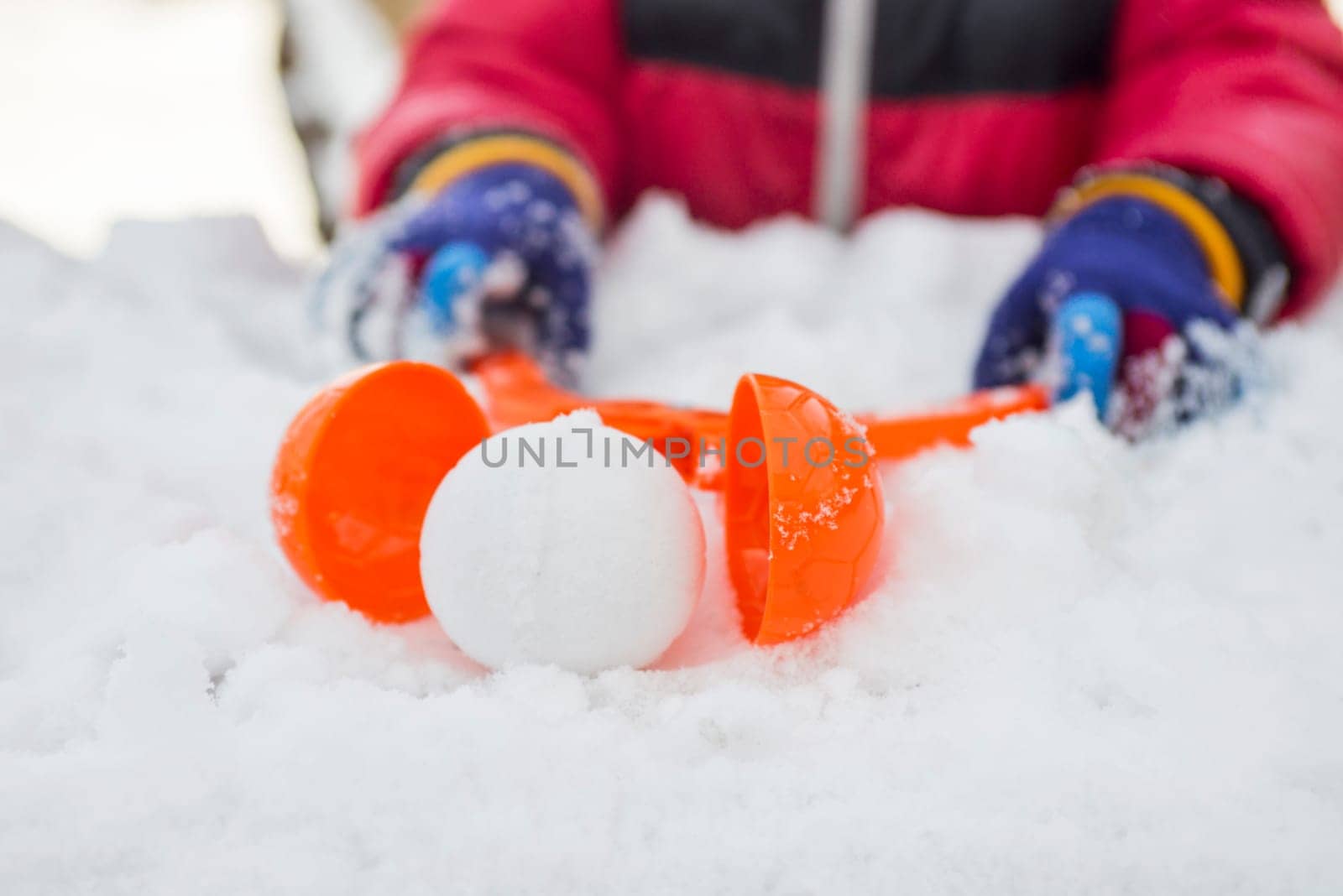 A device for sculpting snowballs in childrens hands against a background of snow. Childrens winter games of snowballs.