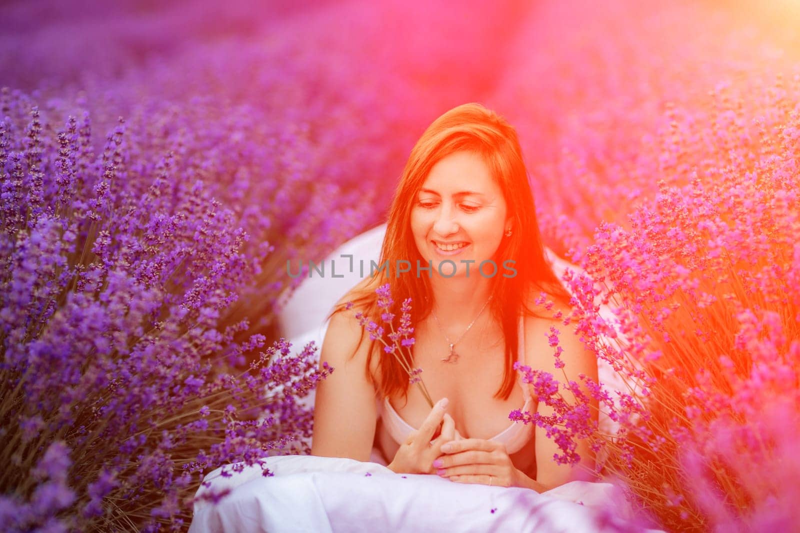 Woman lavender field. A middle-aged woman sits in a lavender field and enjoys aromatherapy. Aromatherapy concept, lavender oil, photo session in lavender.