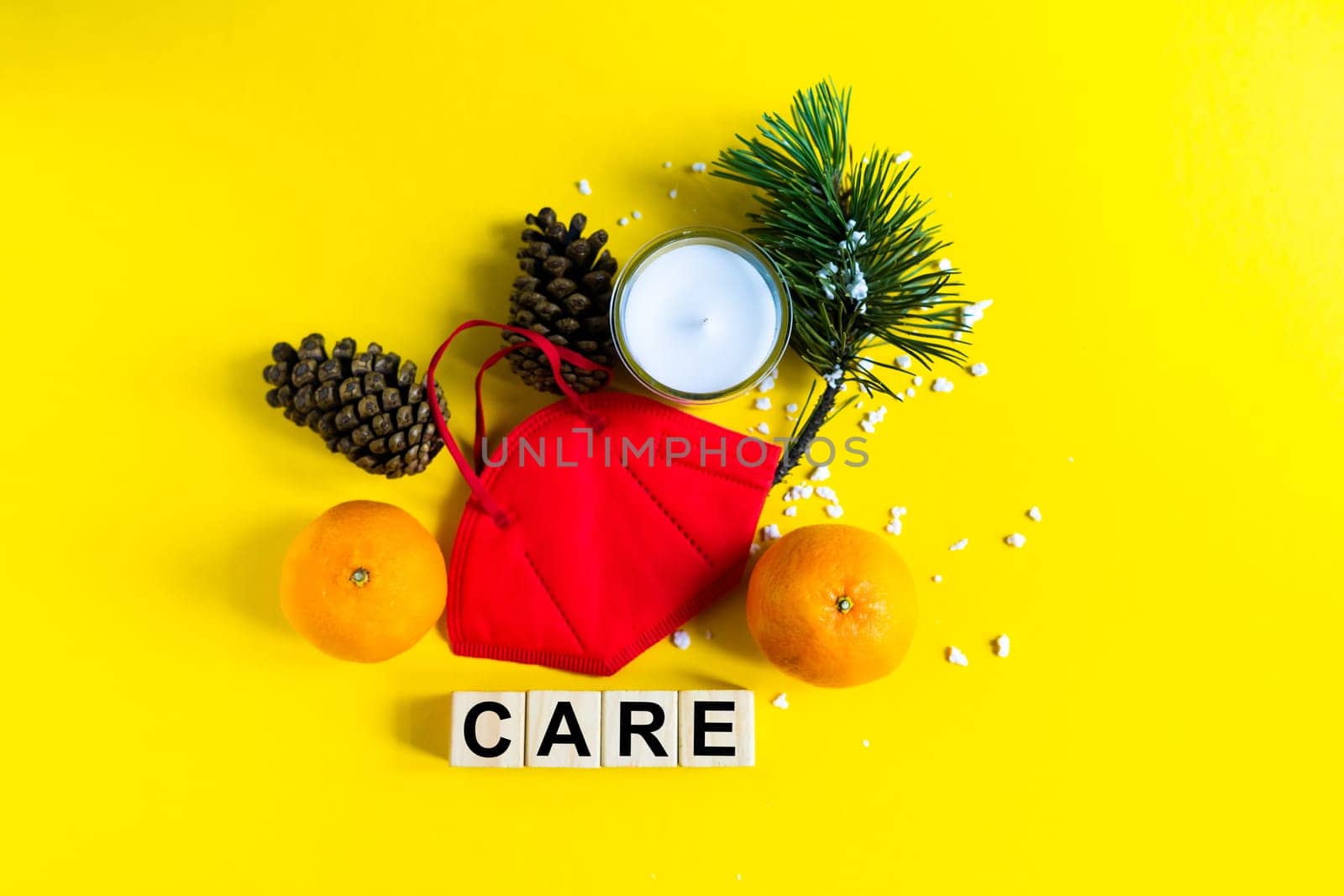 Tangerines lie in medical mask among the branches of the Christmas tree, word Care wooden cubes