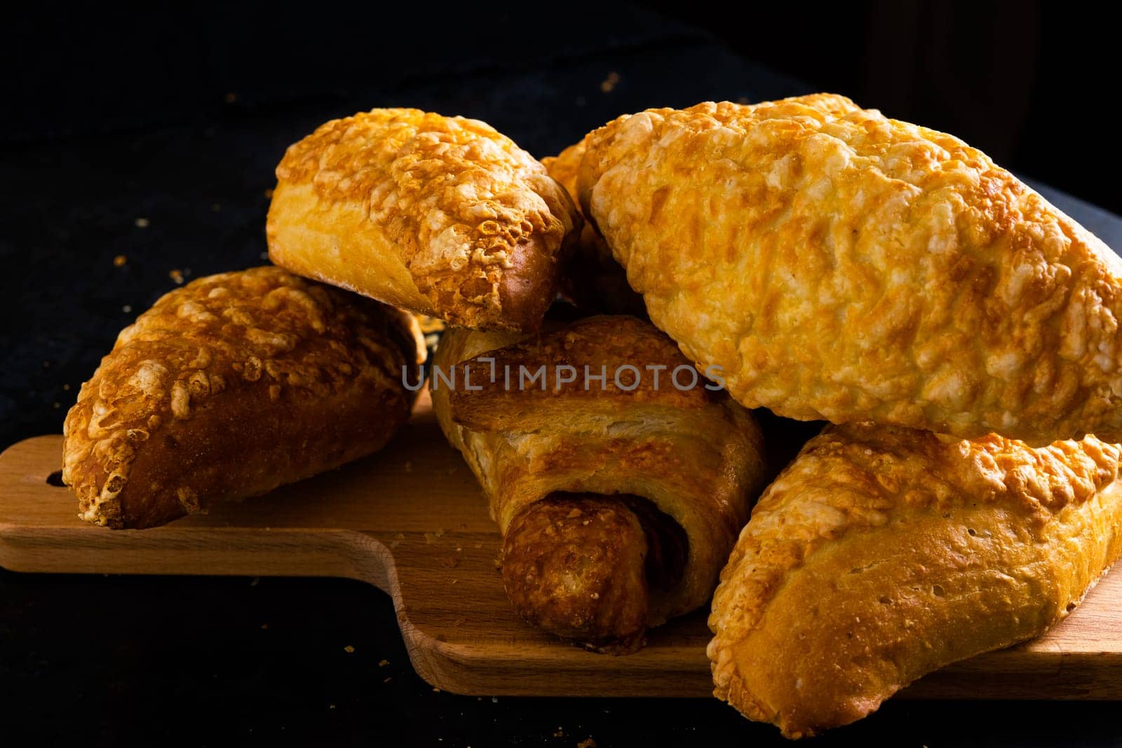 Freshly backed french croissant shiny in the rays of morning sun, dark background, kitchen