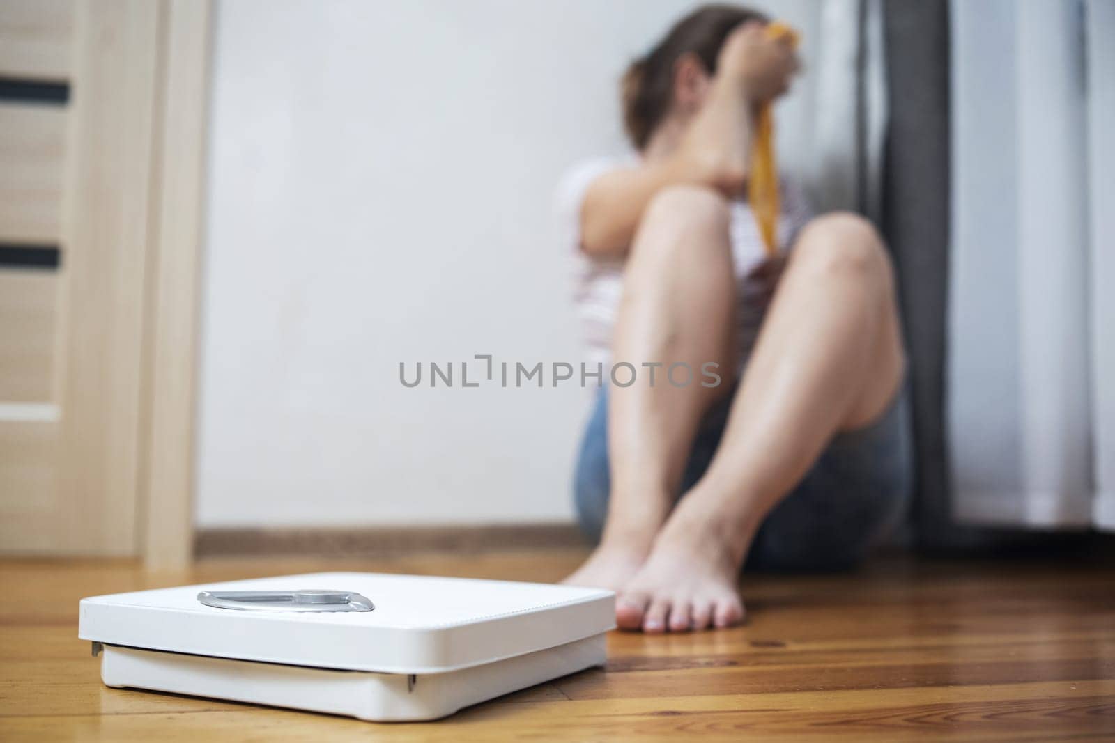 White scale and depression, upset and sad woman with measuring tape on wooden floor.